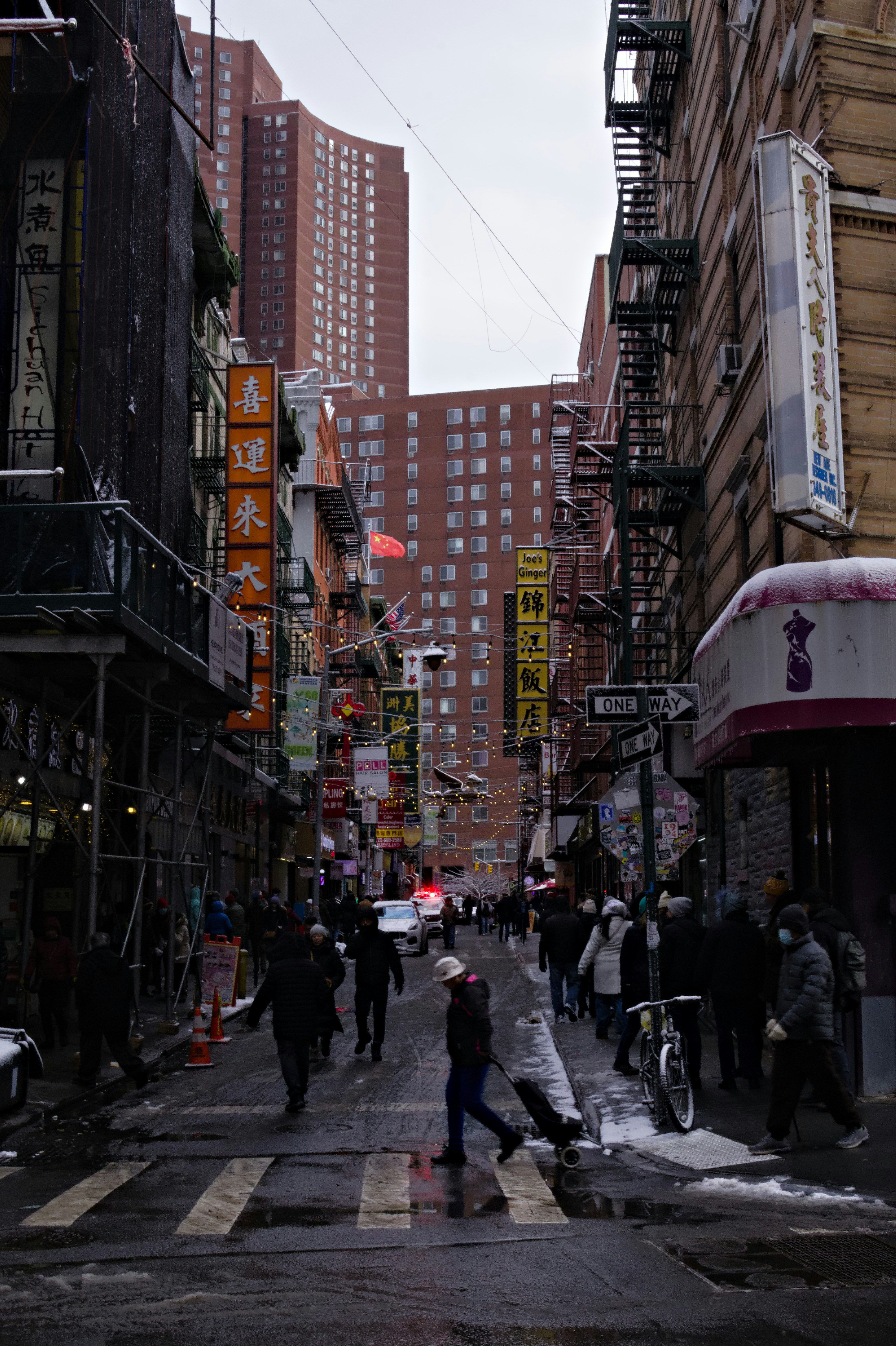 People crossing a street in a city with tall buildings.