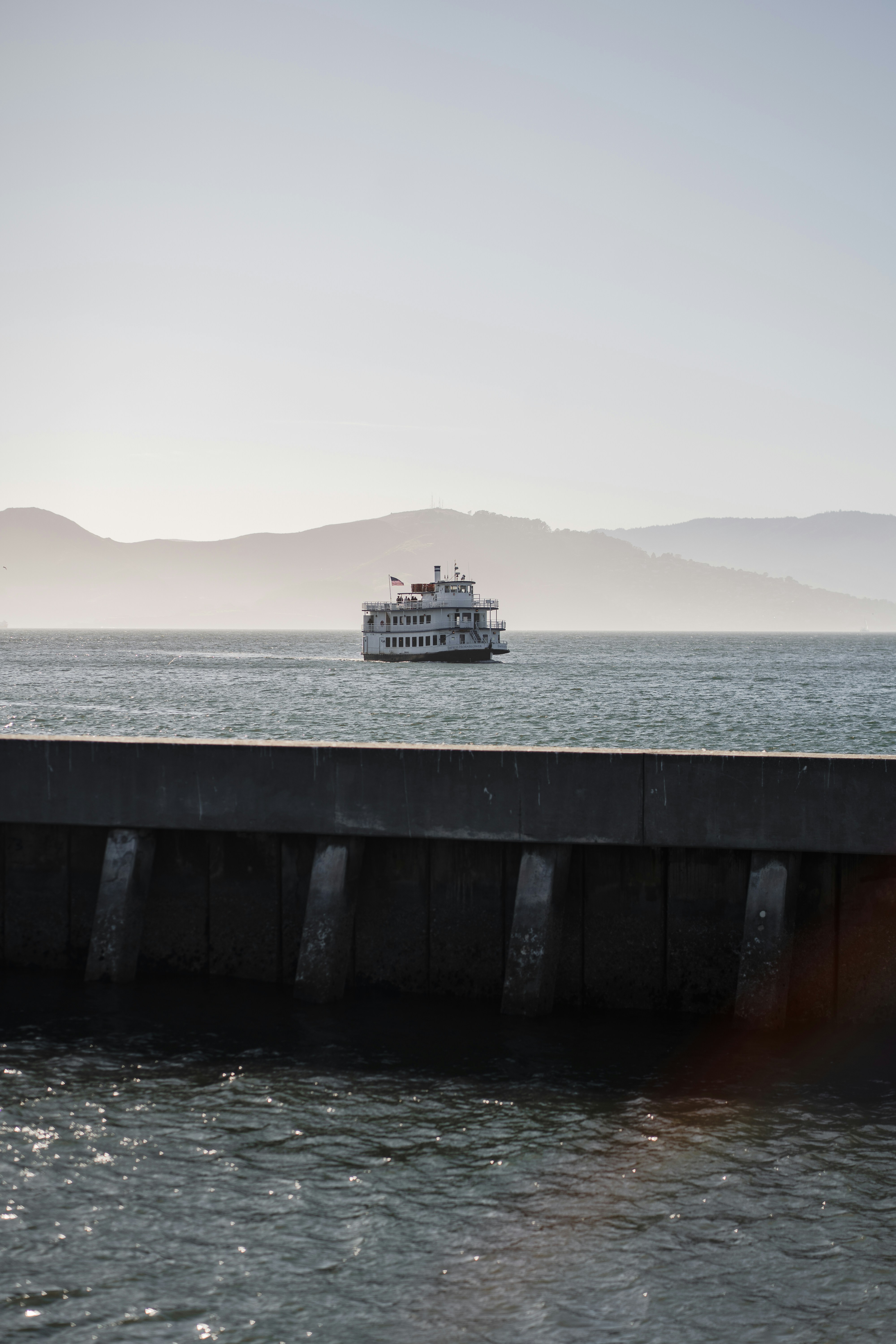A white boat sails on the water near mountains.