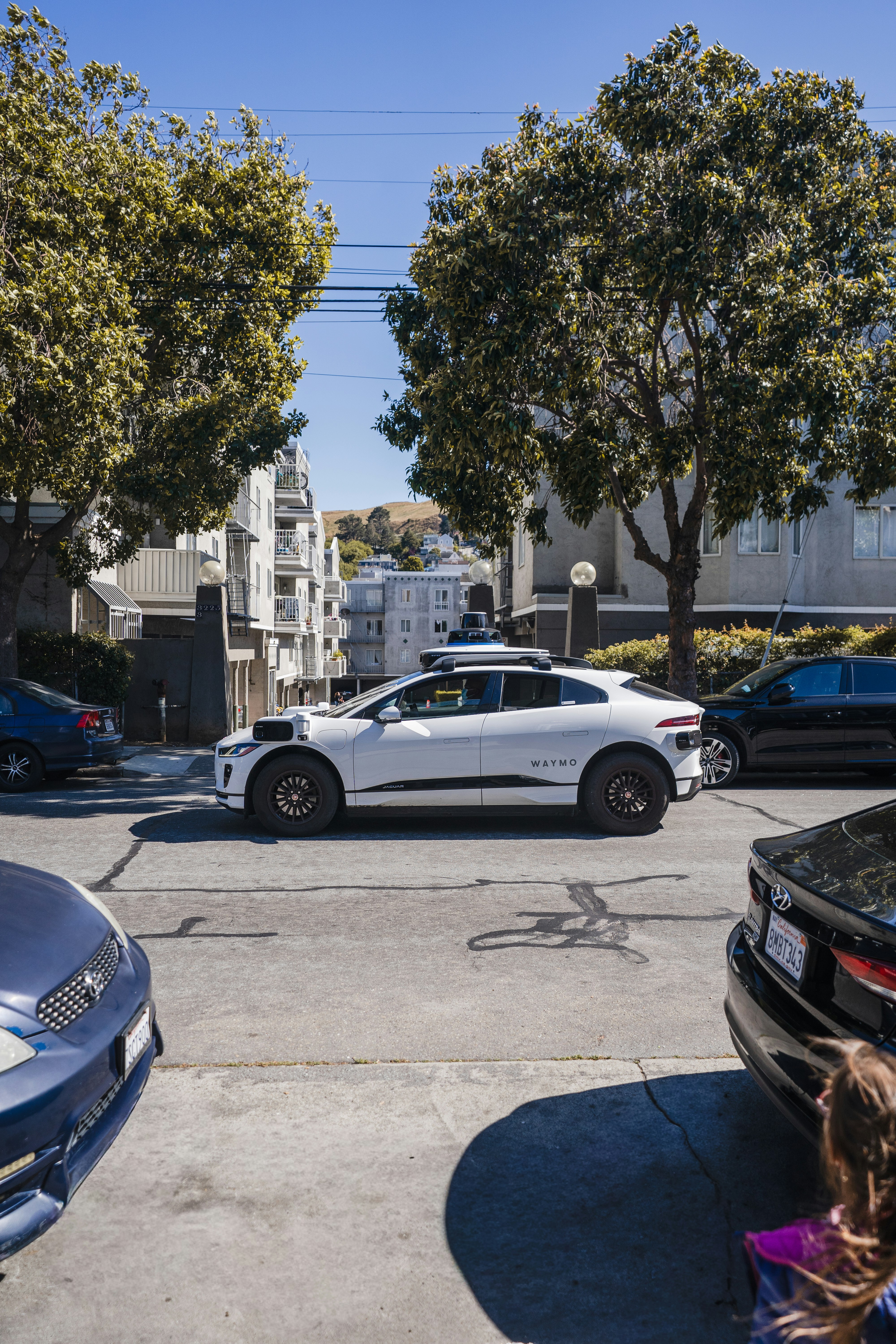 A white self-driving car on a city street.