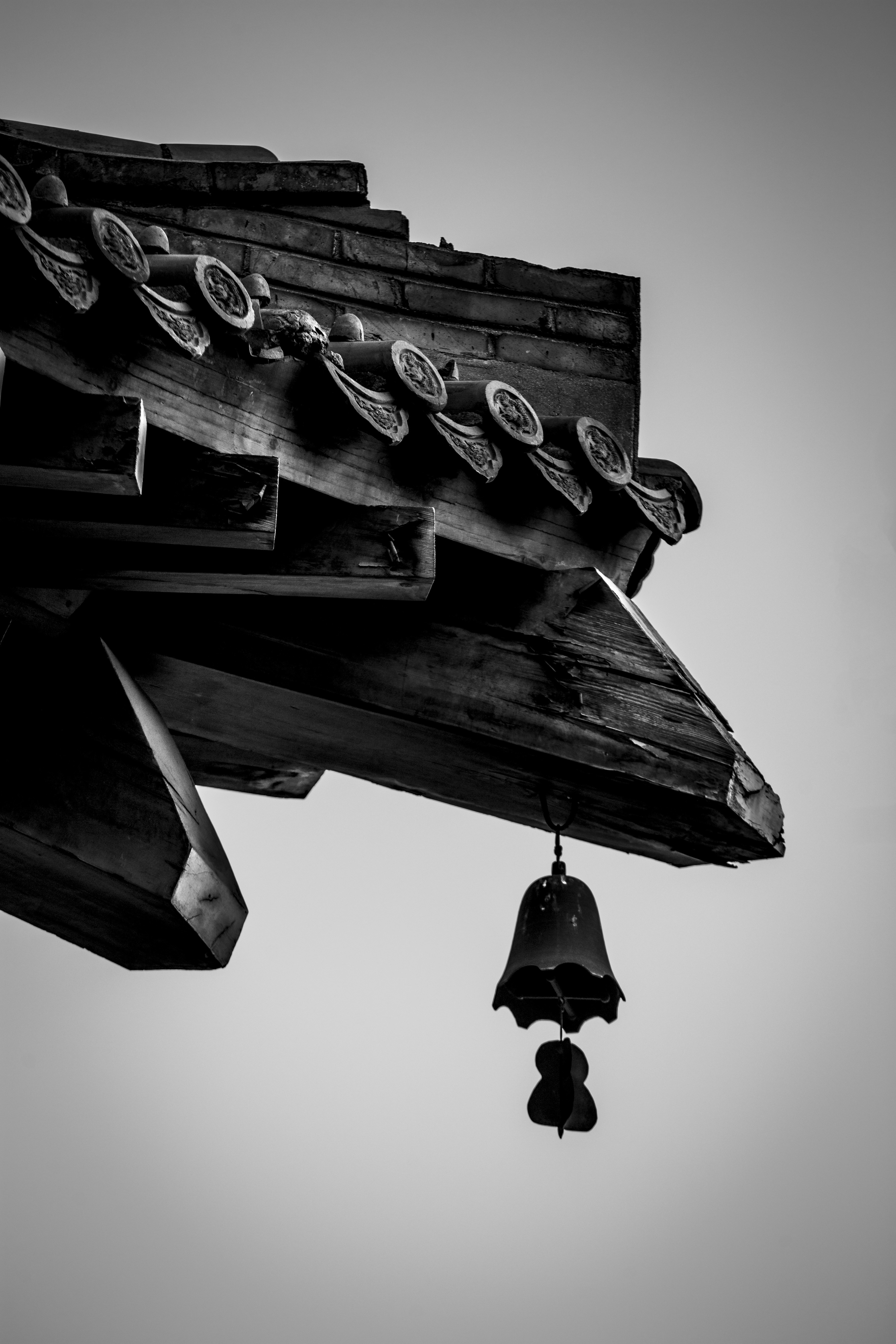Primer plano de una campana ornamentada colgando de un tejado de madera.