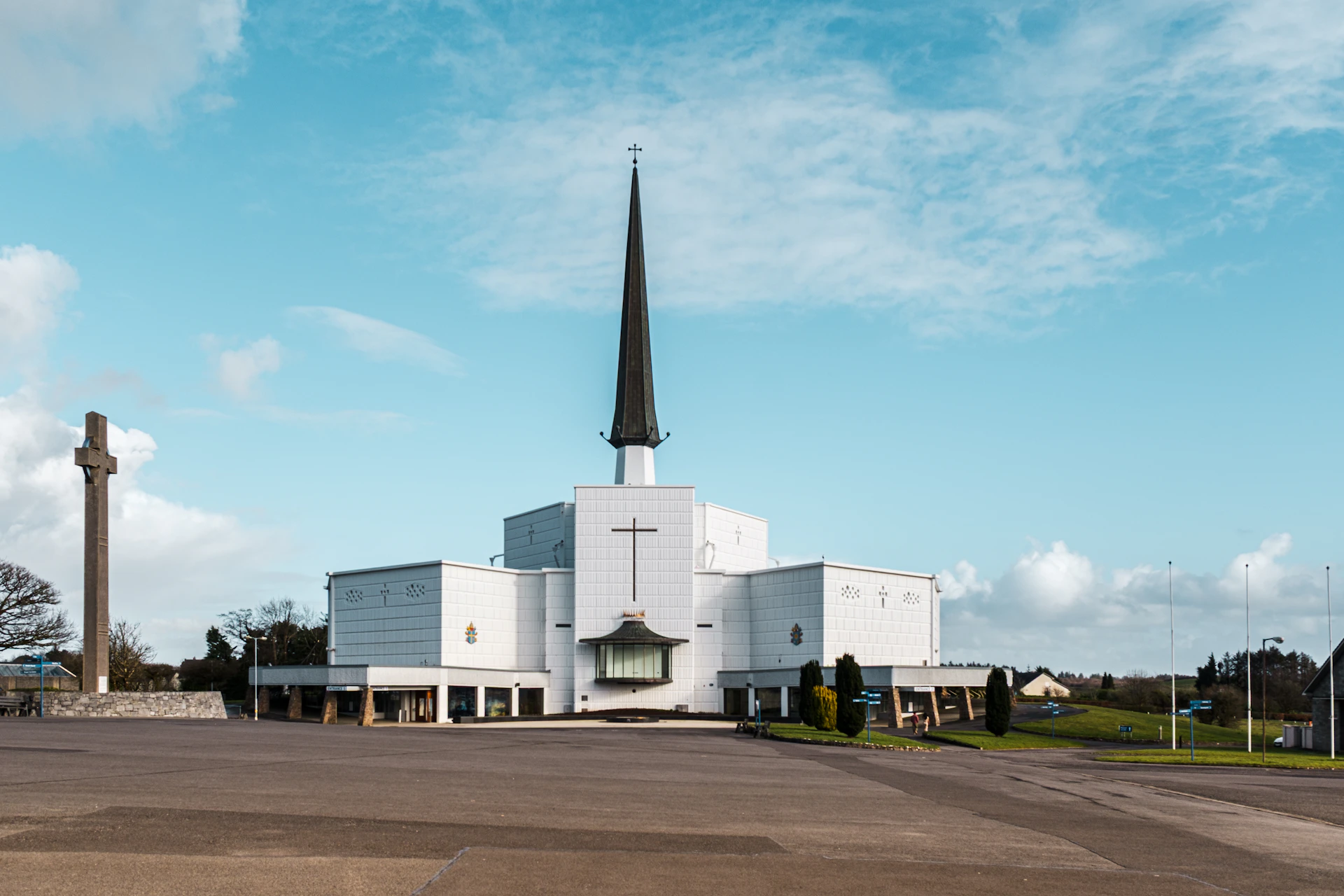 Modern white church building with tall steeple and cross
