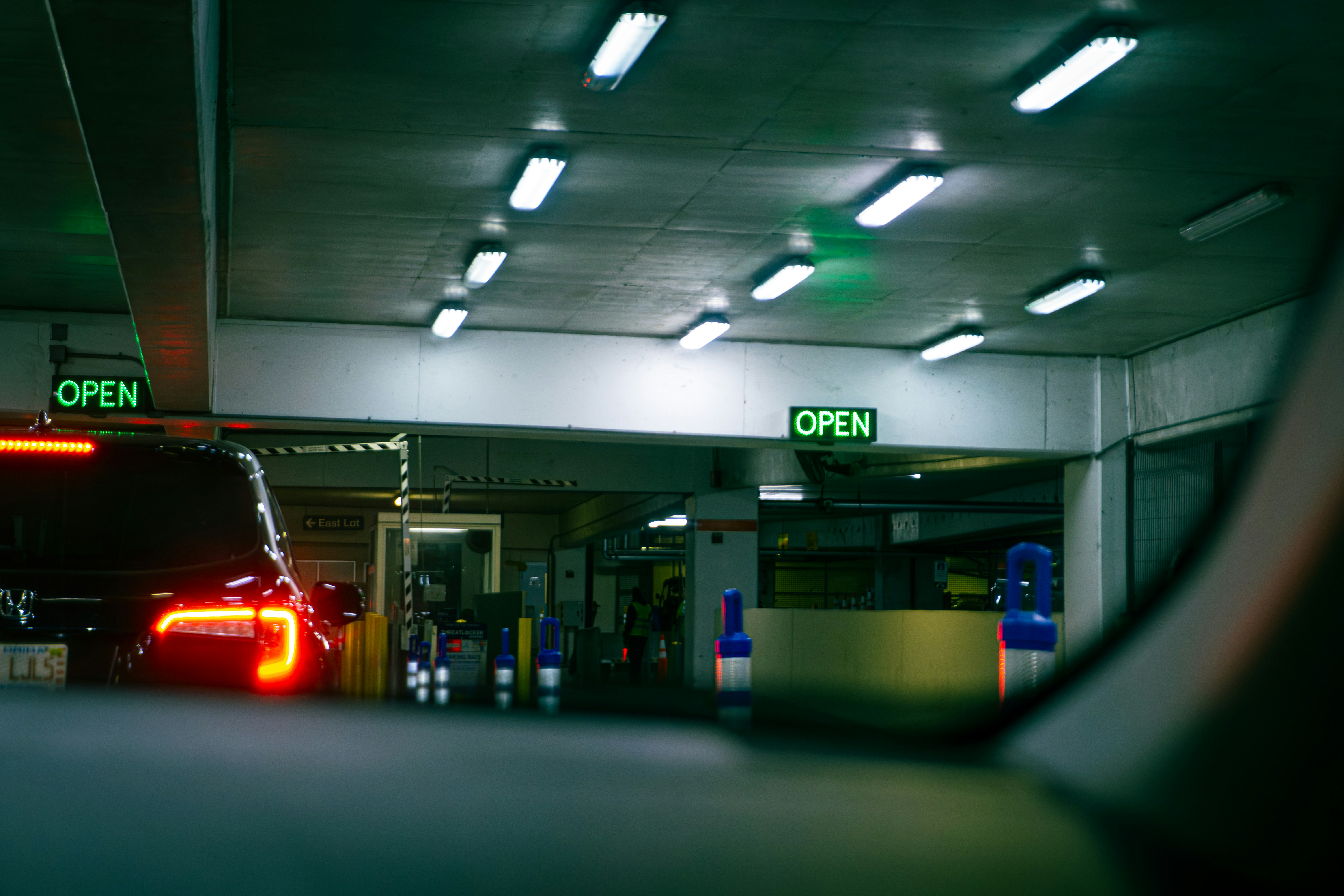 Car entering a dimly lit parking garage with open signs.