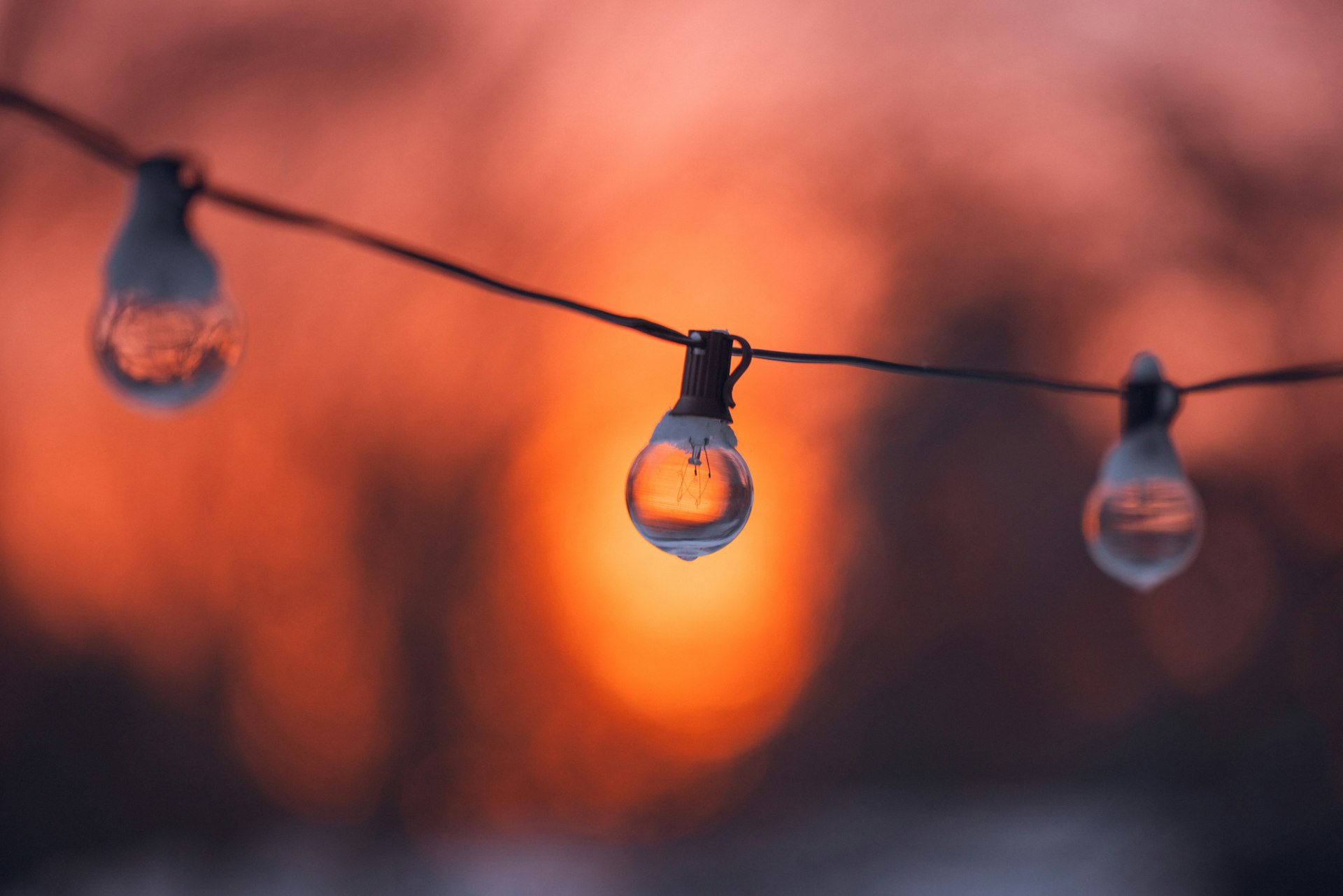 Three light bulbs on a string at sunset