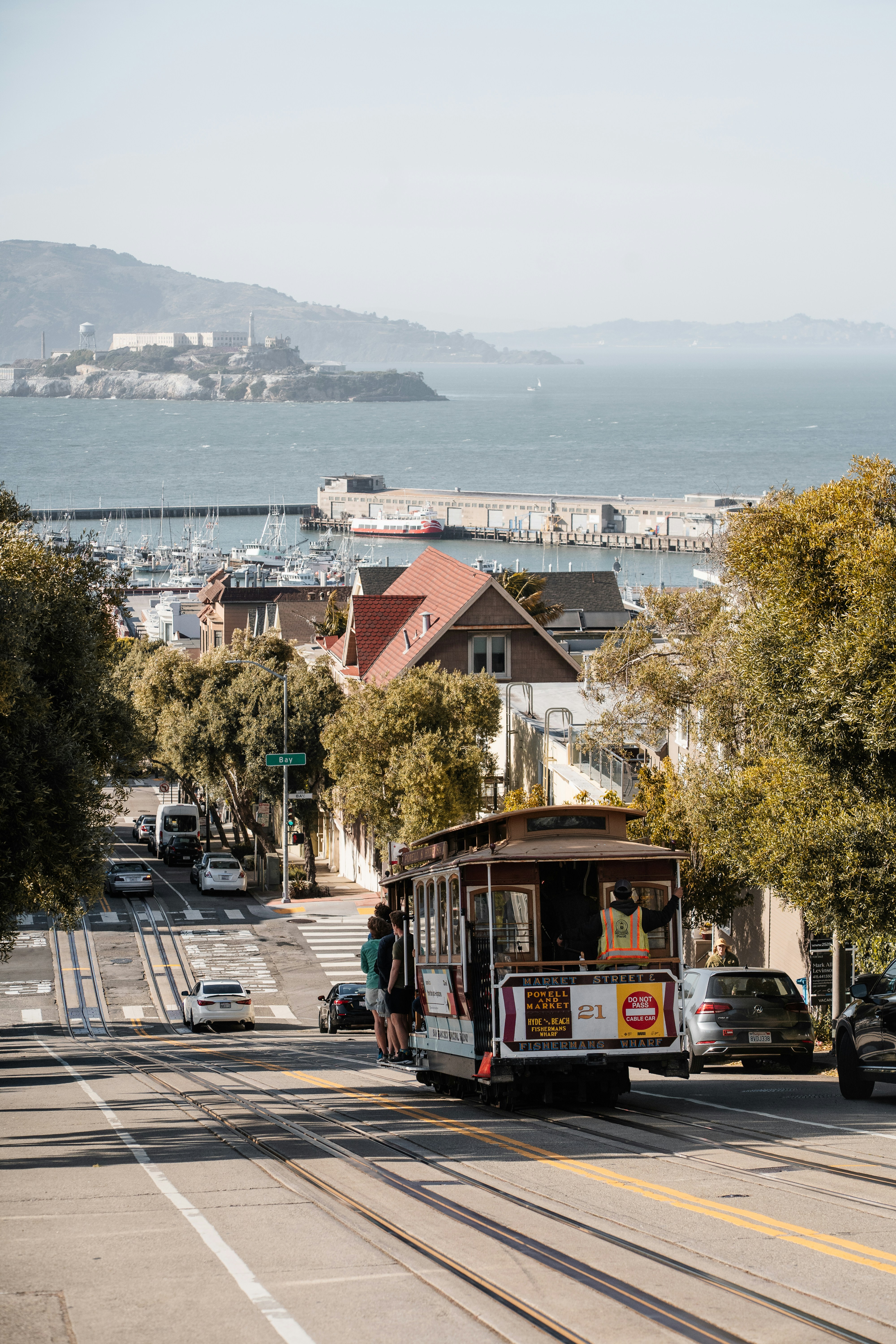 Funivia che sale per una strada di San Francisco con l'isola di Alcatraz.