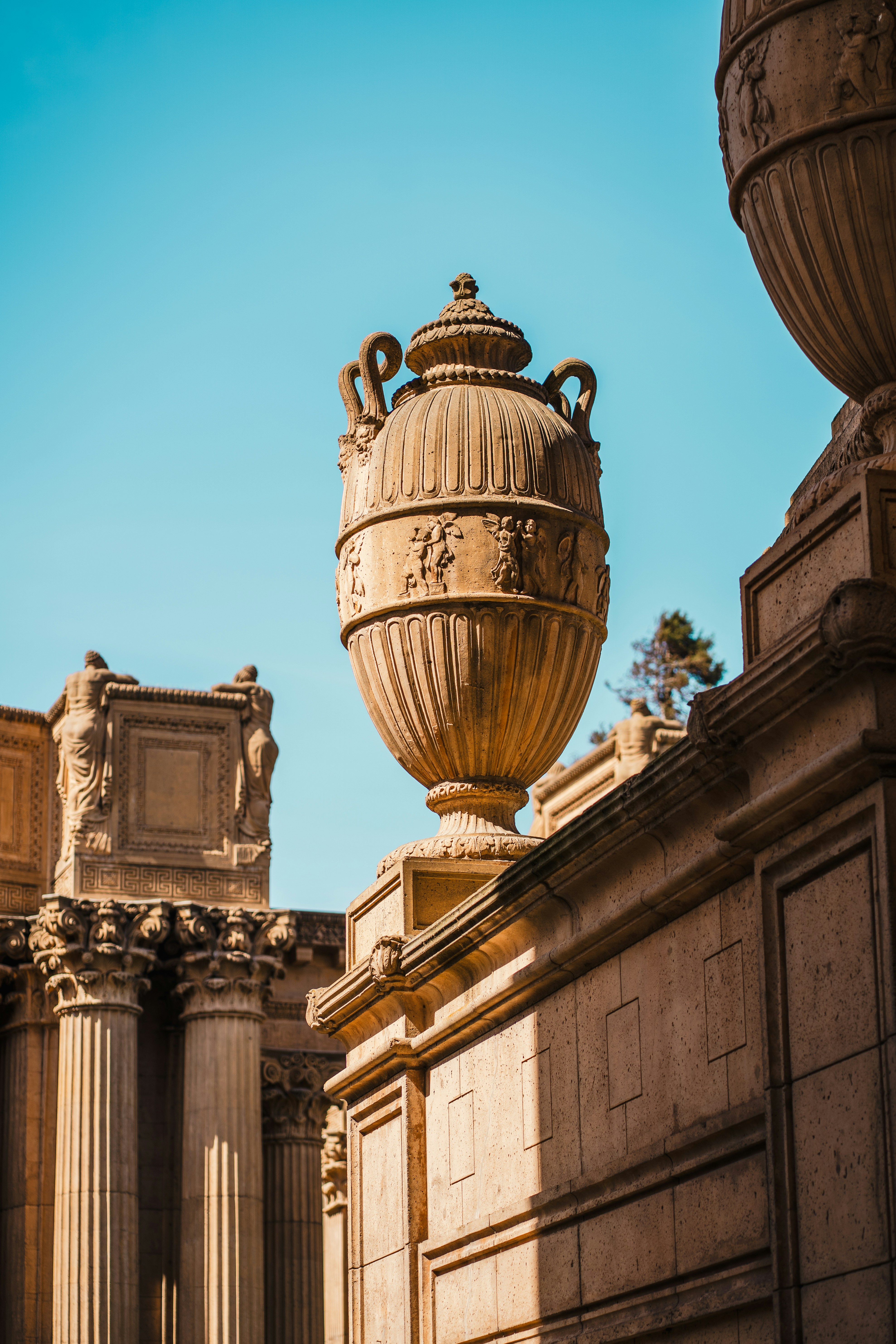 Urna ornamentada sobre arquitectura clásica bajo un cielo azul claro