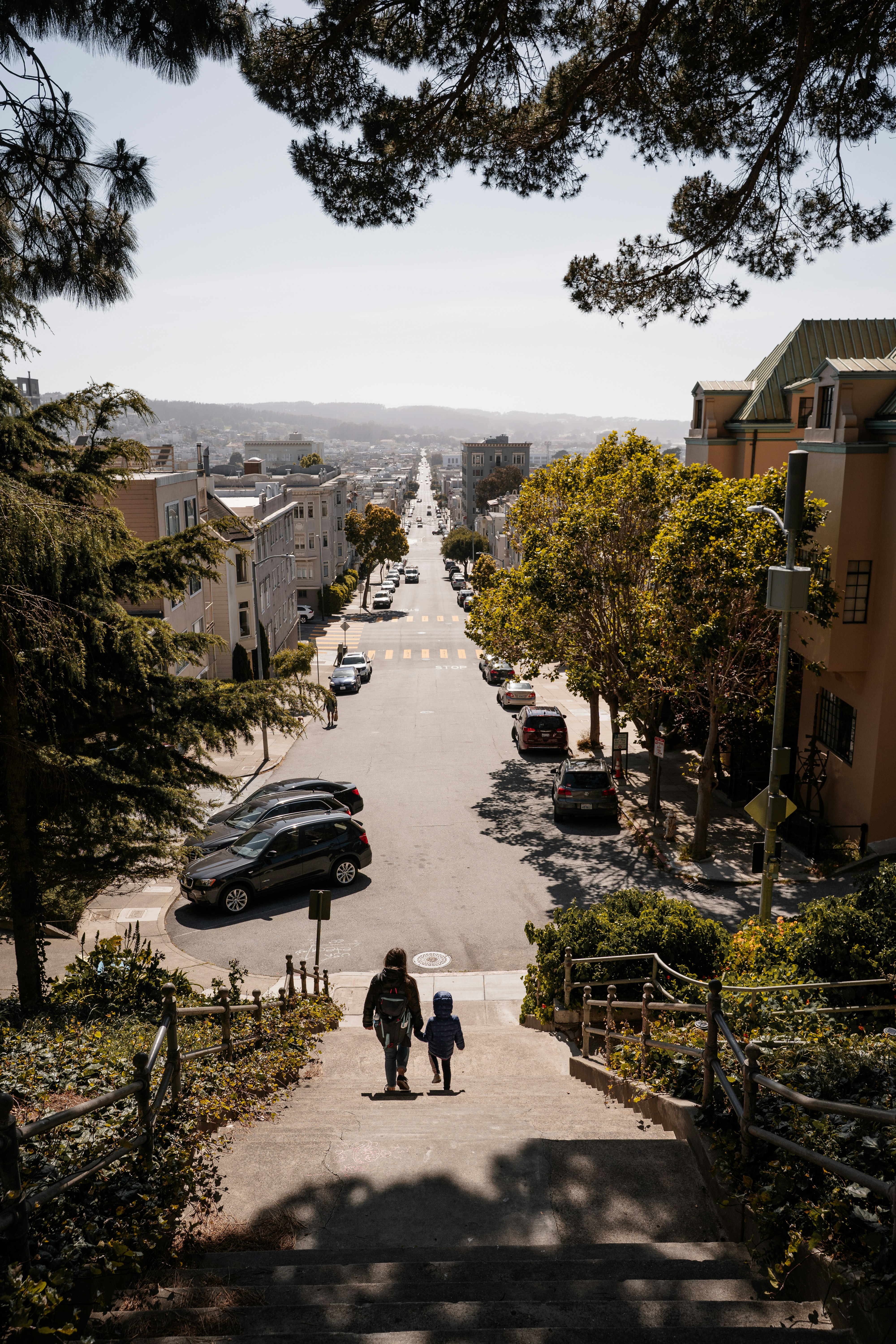 Two people walk down a steep city street