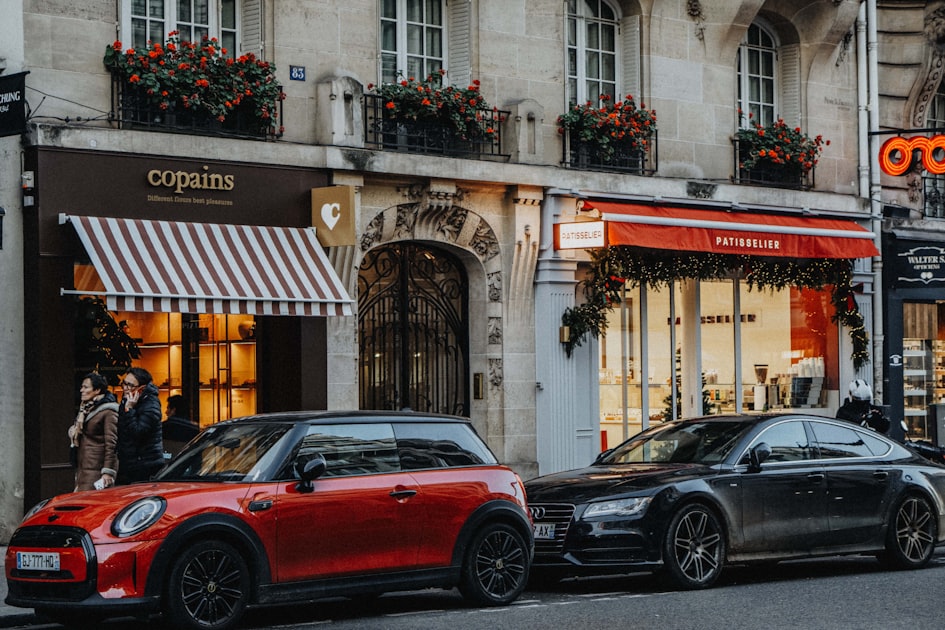 Two cars parked on a street in front of shops