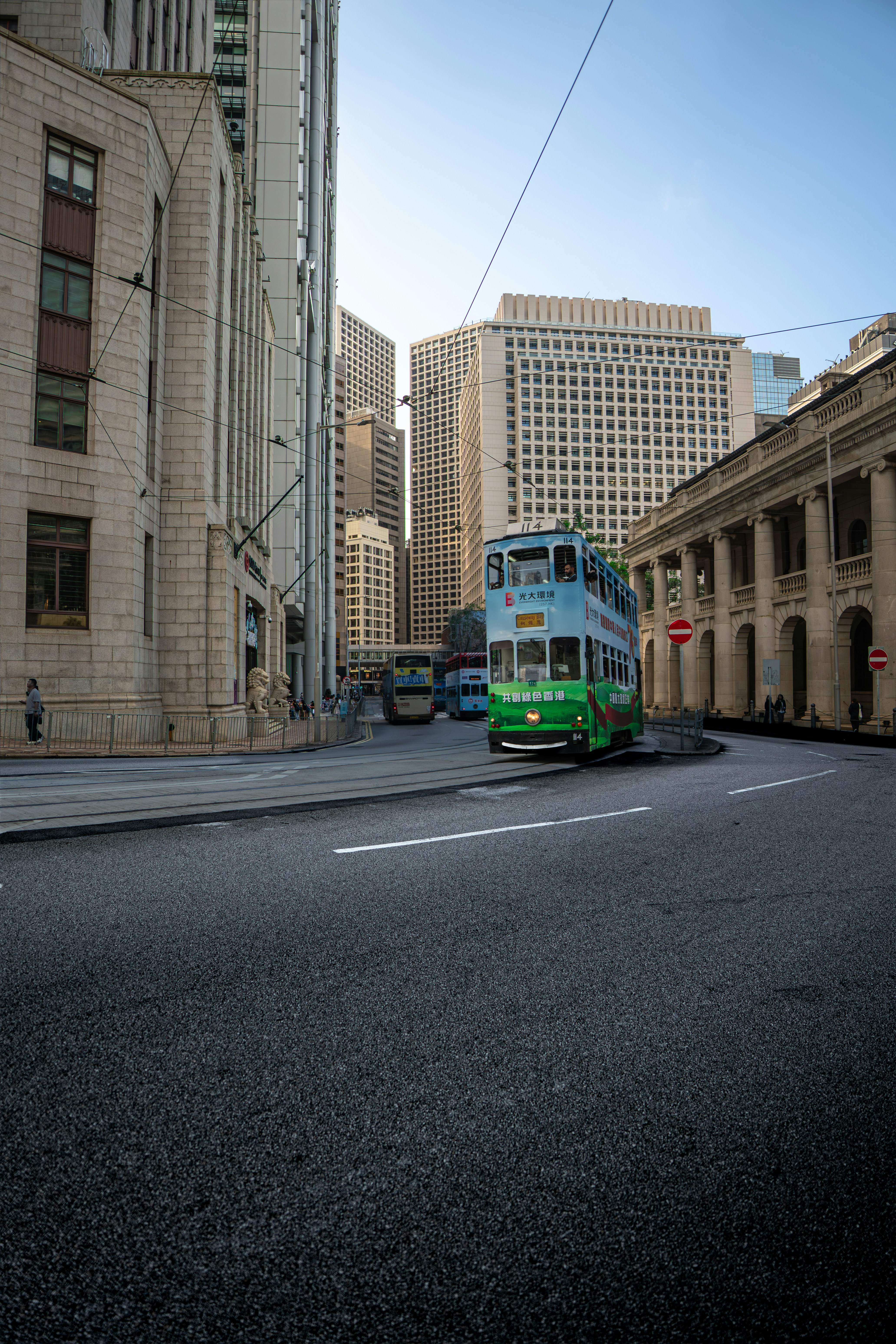 A double-decker tram drives down a city street.
