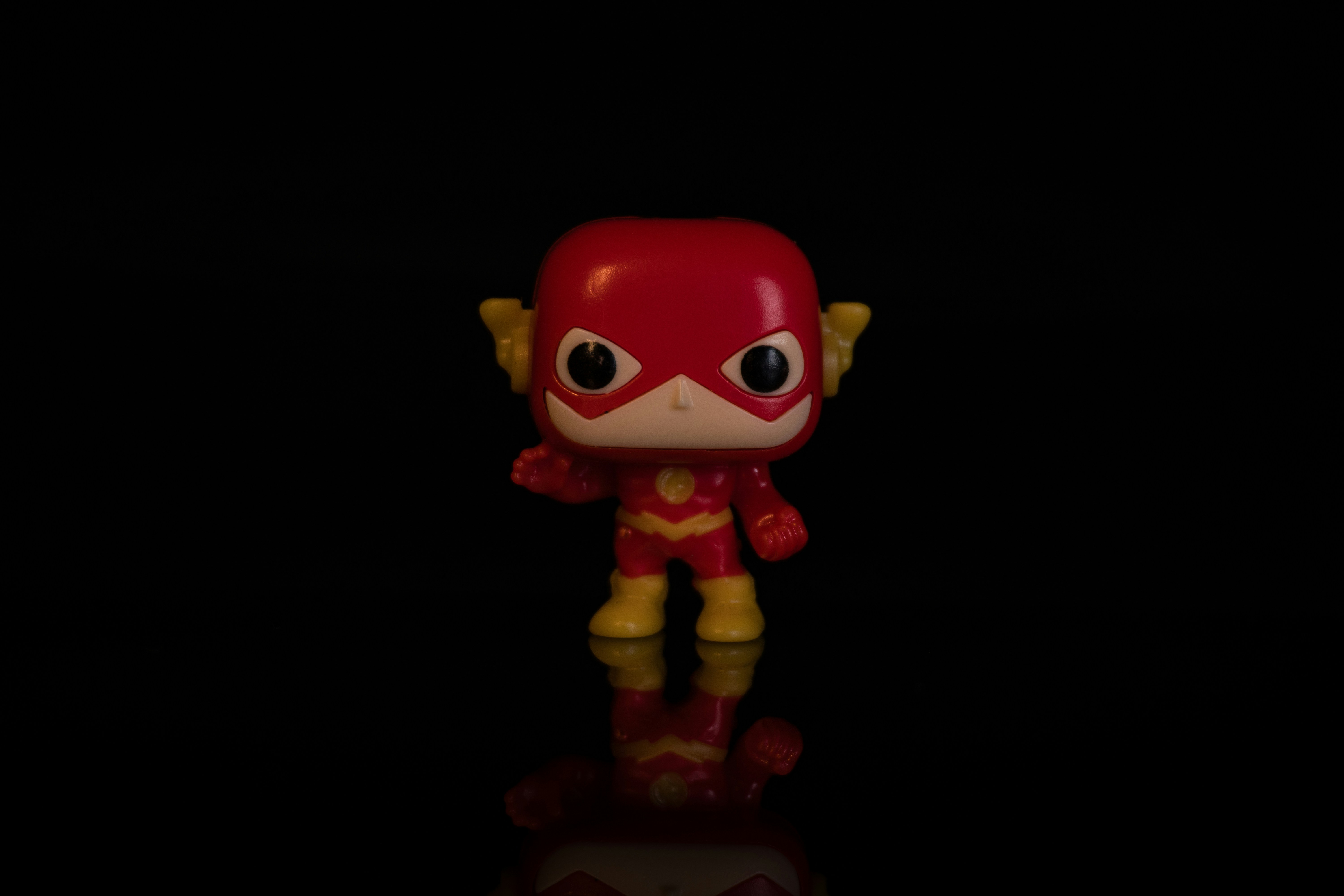 Uma pequena figura de brinquedo de flash sobre uma superfície refletiva.
