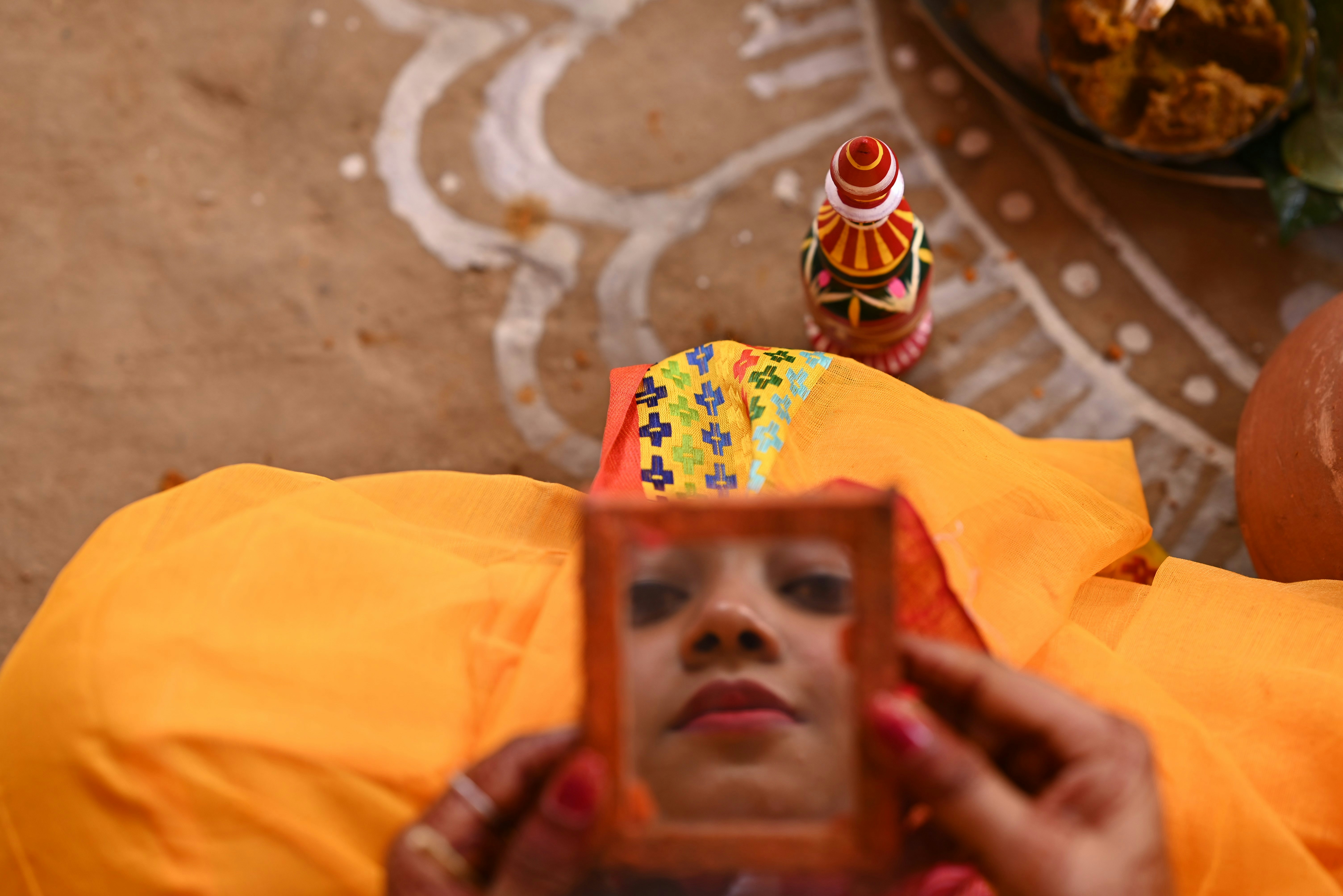 Frau, die in einen kleinen Spiegel mit traditionellen Dekorationen blickt