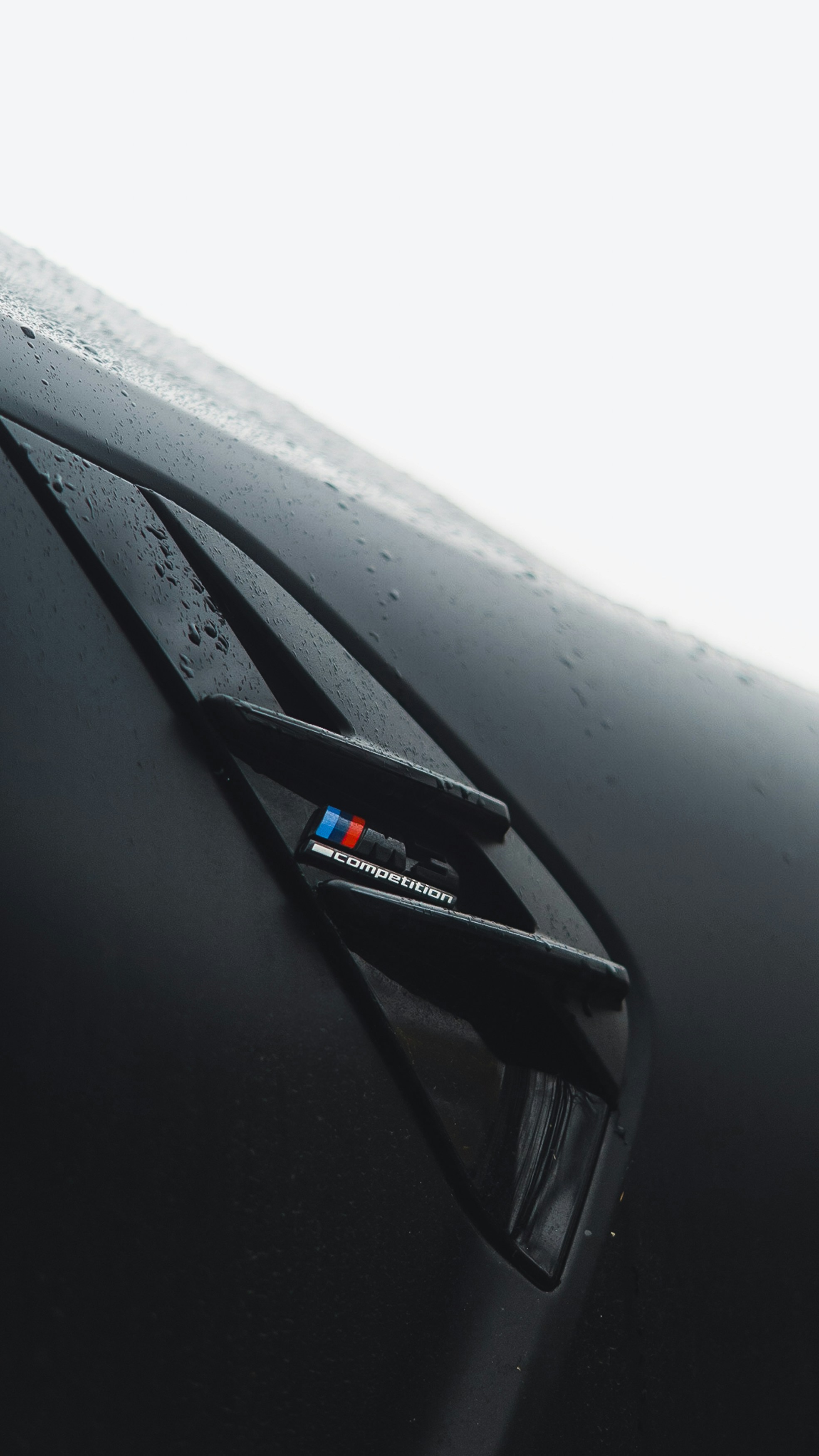 Black car with water droplets and BMW m logo.
