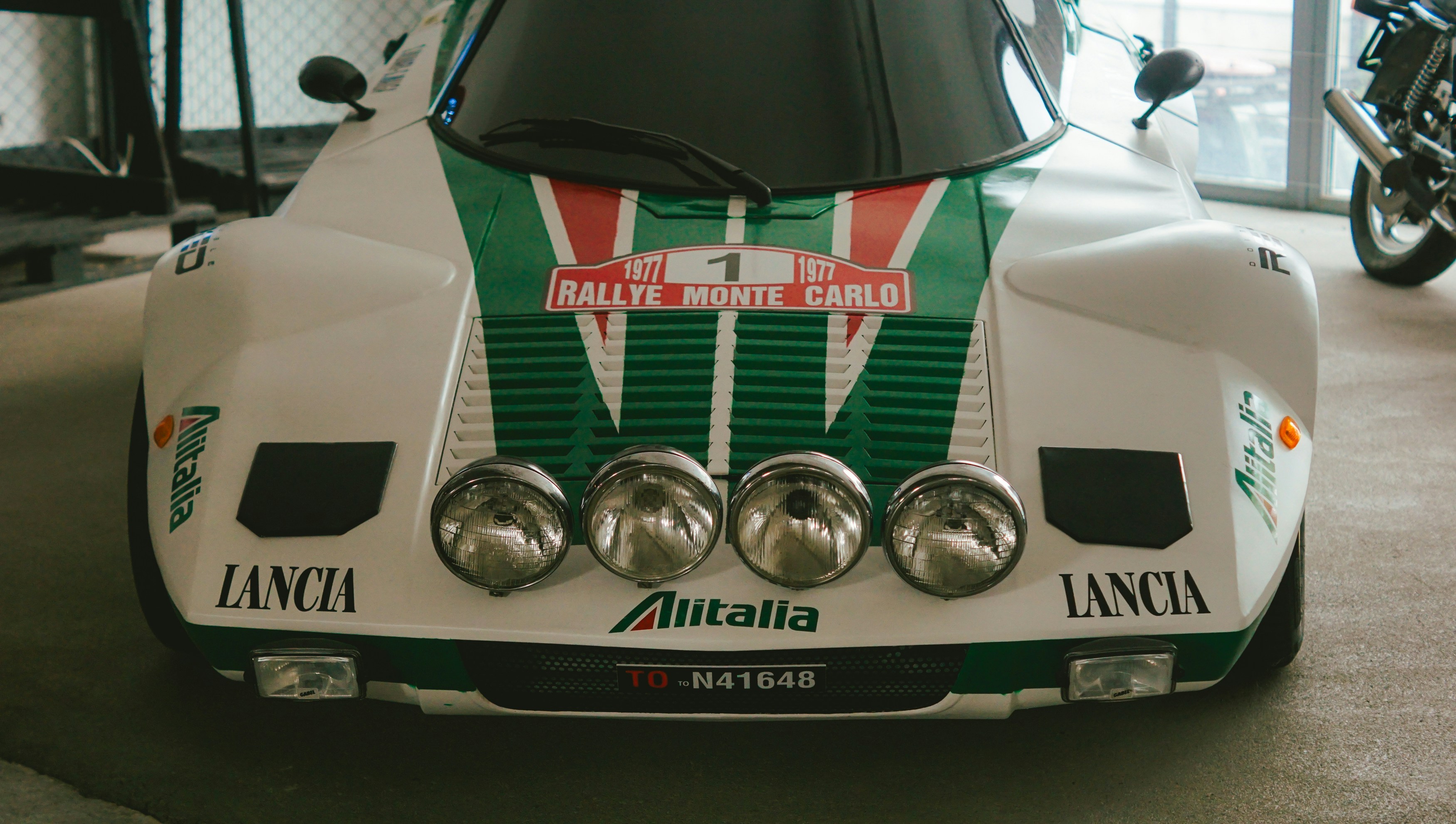 White lancia rally car with green stripes and lights.