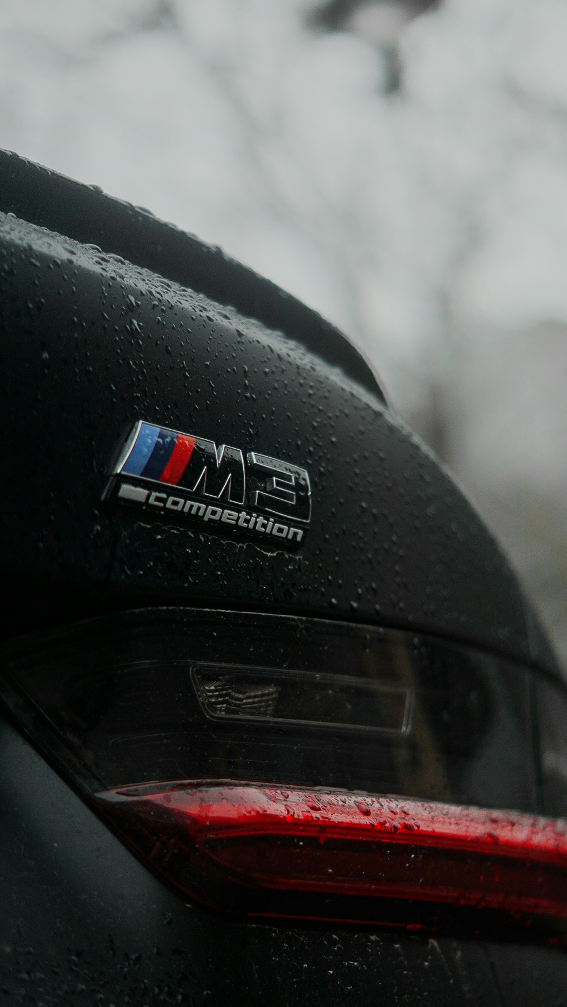BMW m3 competition badge on a wet car