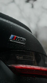 BMW m3 competition badge on a wet car