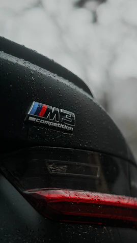 BMW m3 competition badge on a wet car