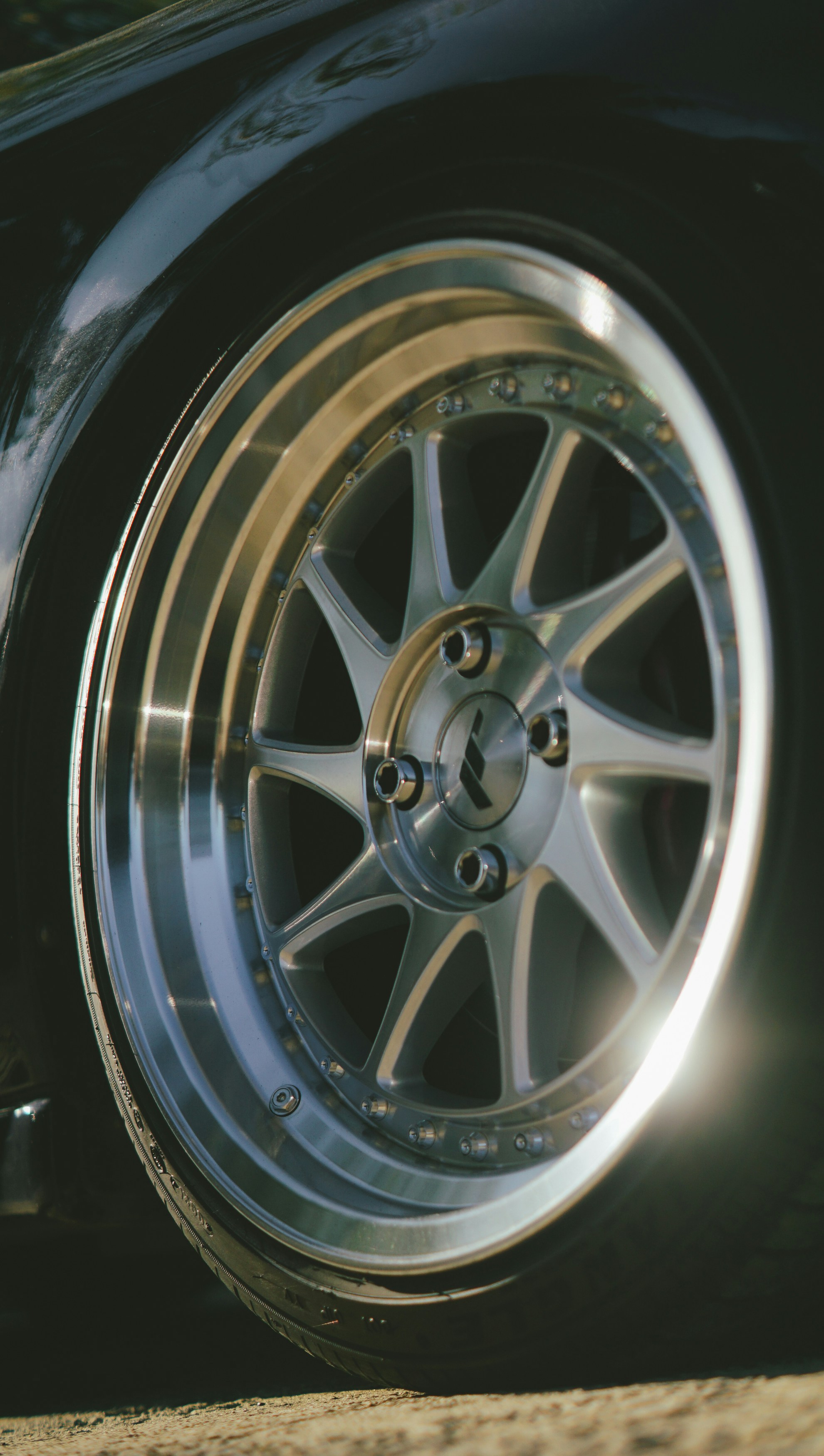 Close-up of a shiny silver car wheel with spokes.