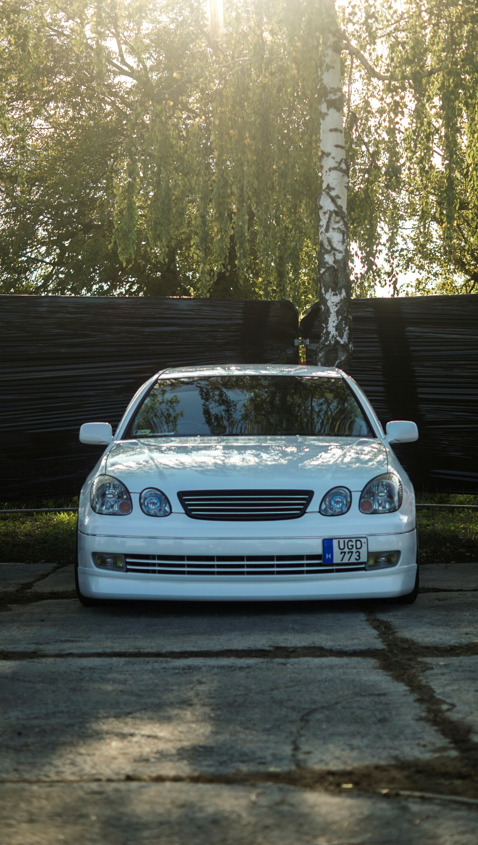 White sedan parked outside on a sunny day.