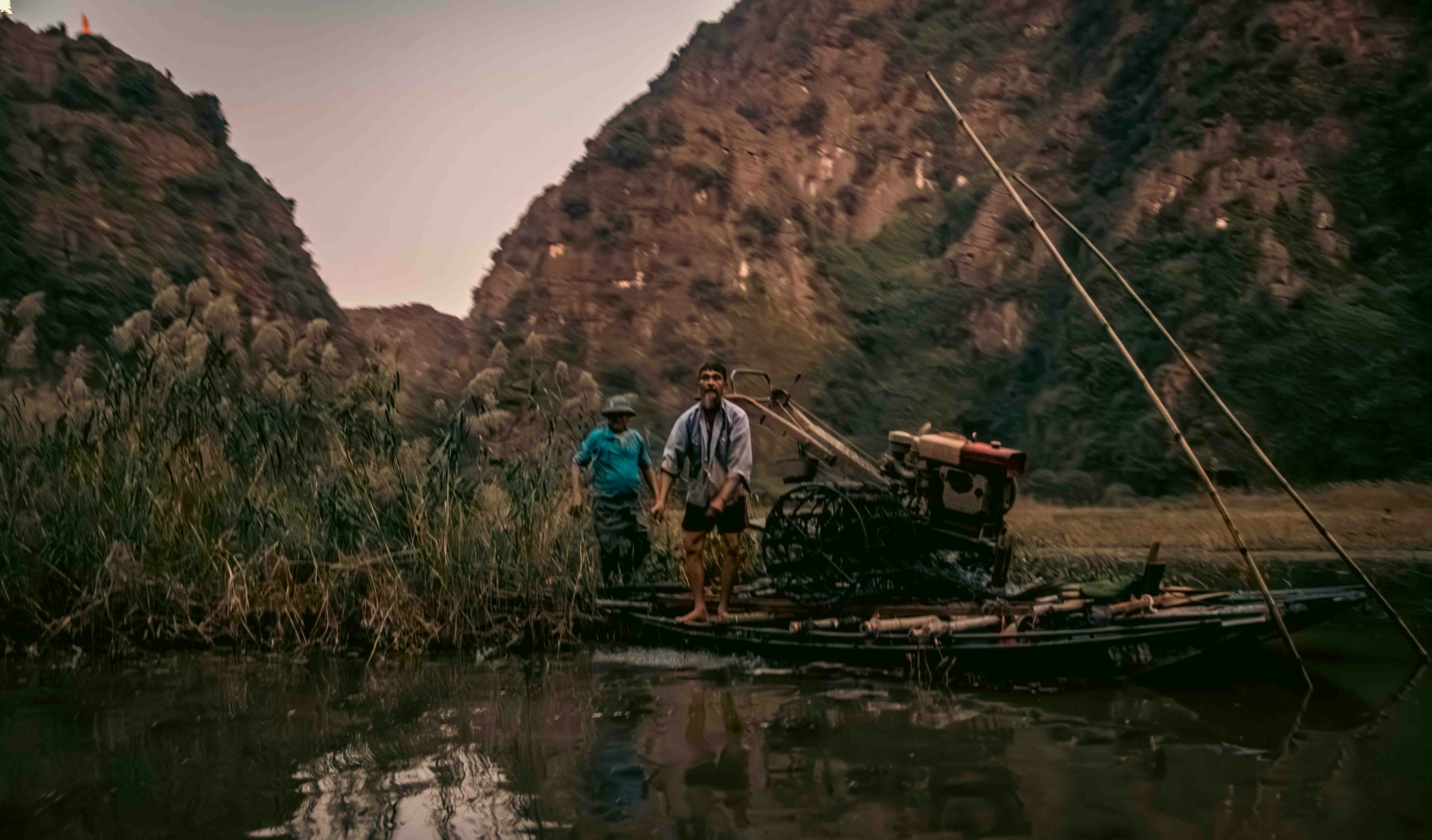 Two men on a boat with mountains in background