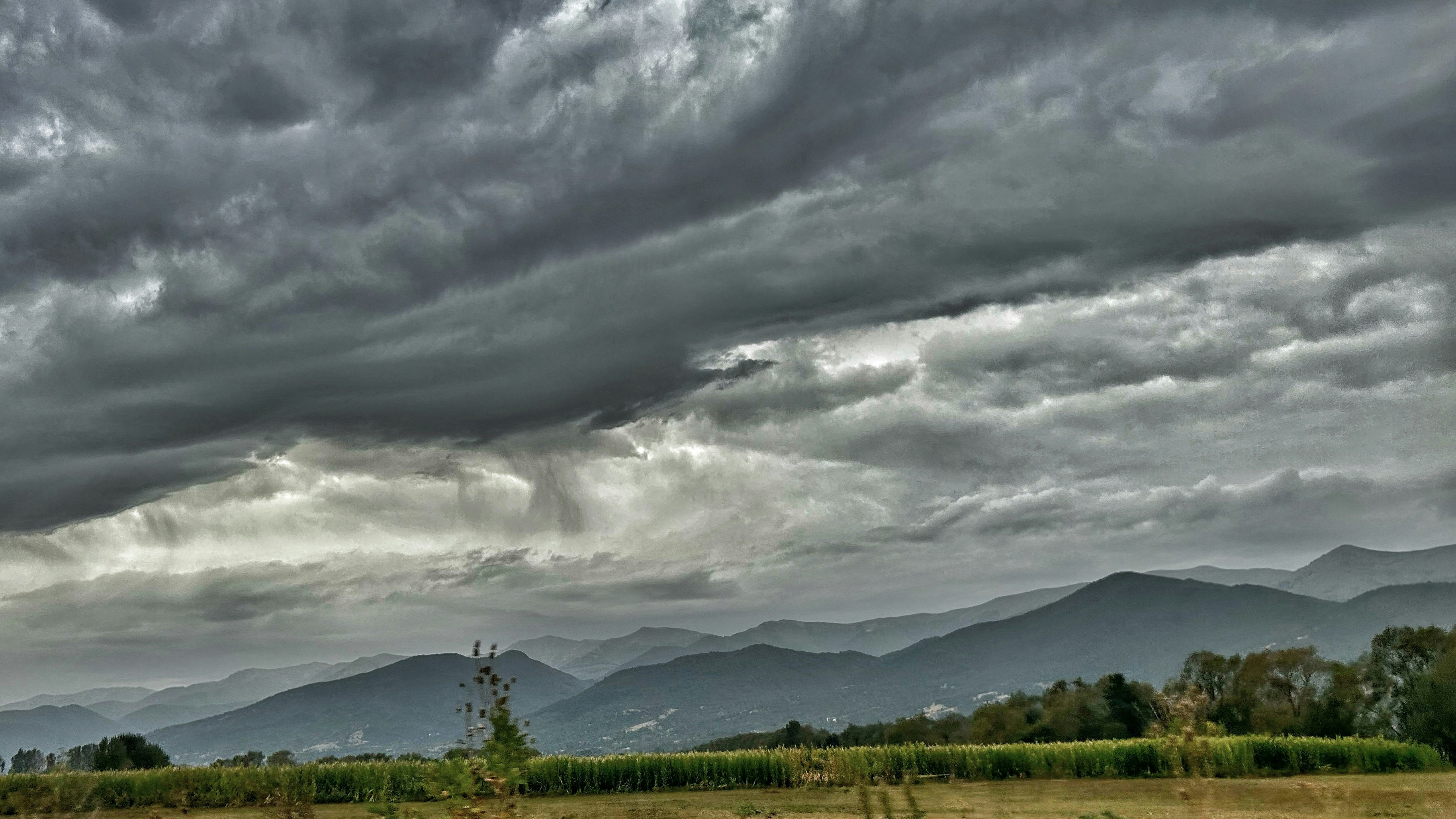 Dark storm clouds gather over distant mountains.