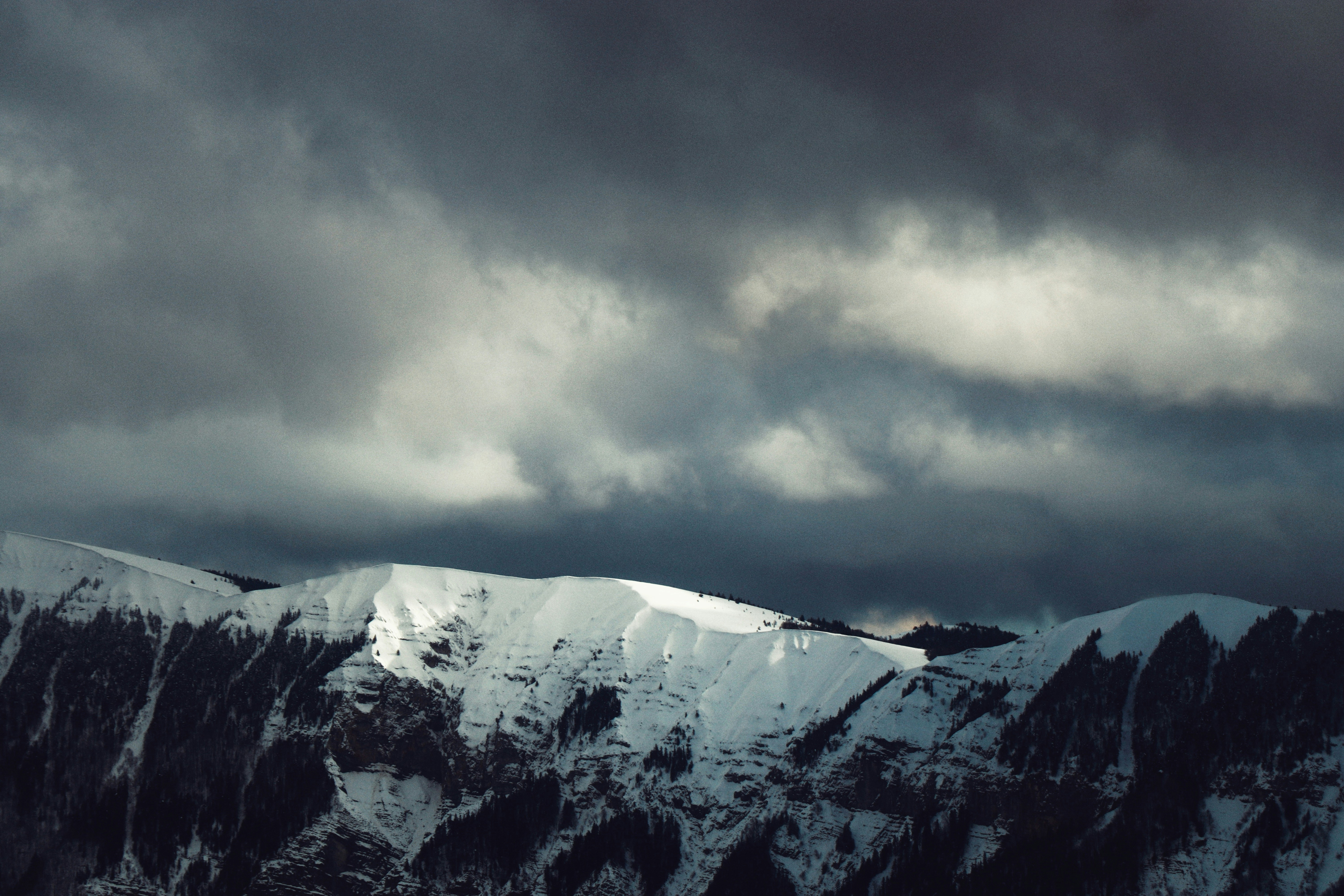 Snow-covered mountains under dramatic dark clouds