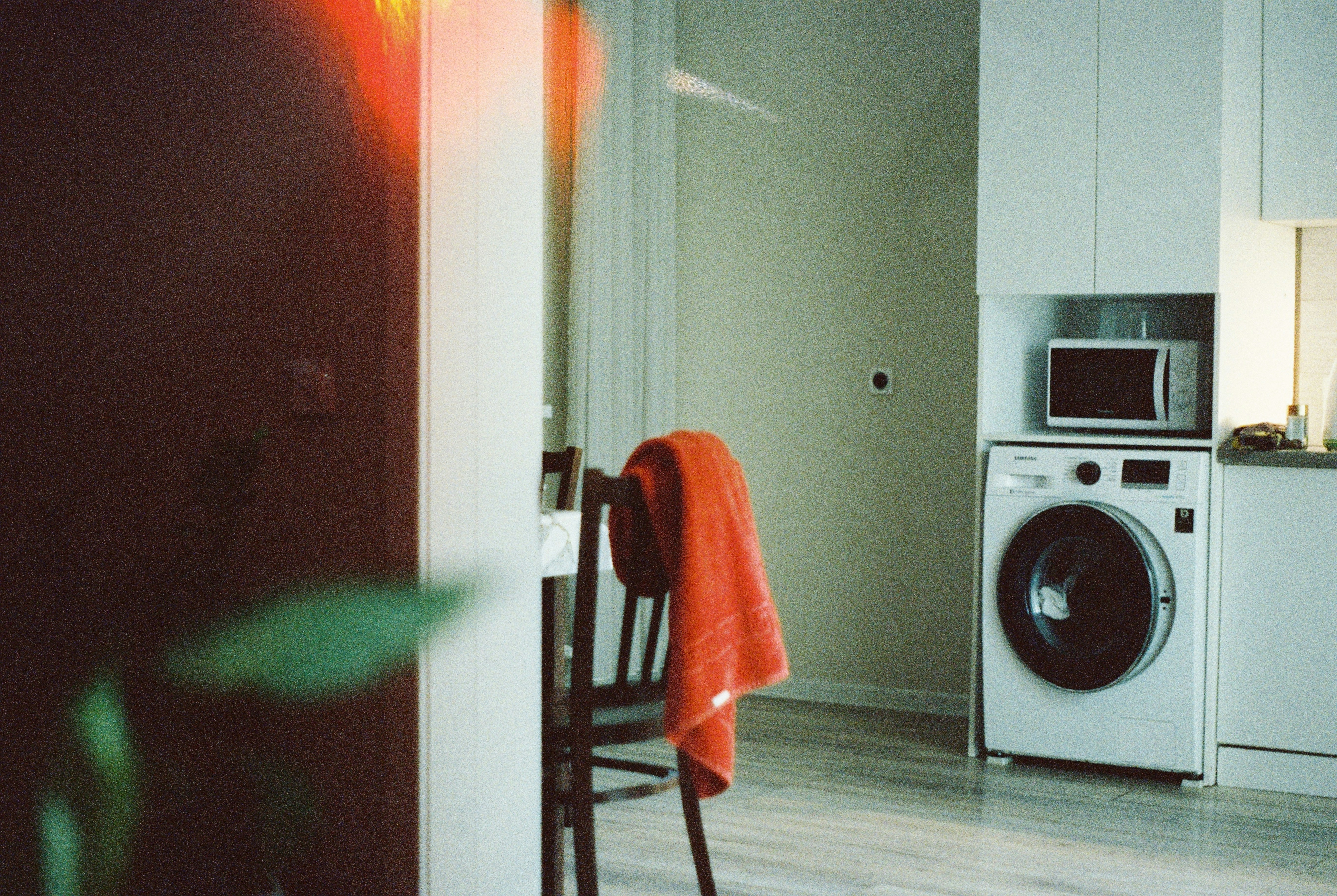 Orange towel draped over a chair next to washing machine.