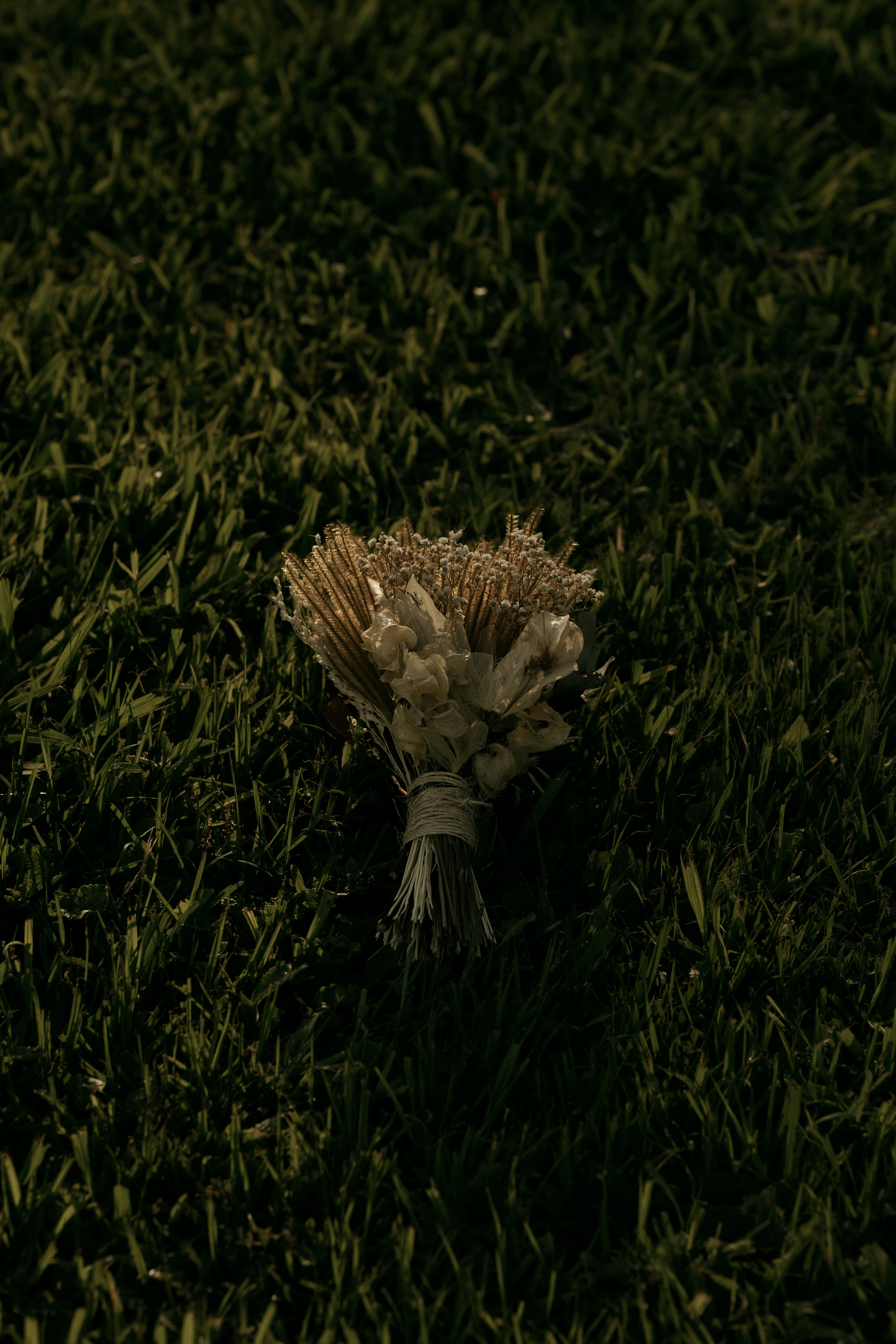 A small bouquet of dried flowers rests on grass.