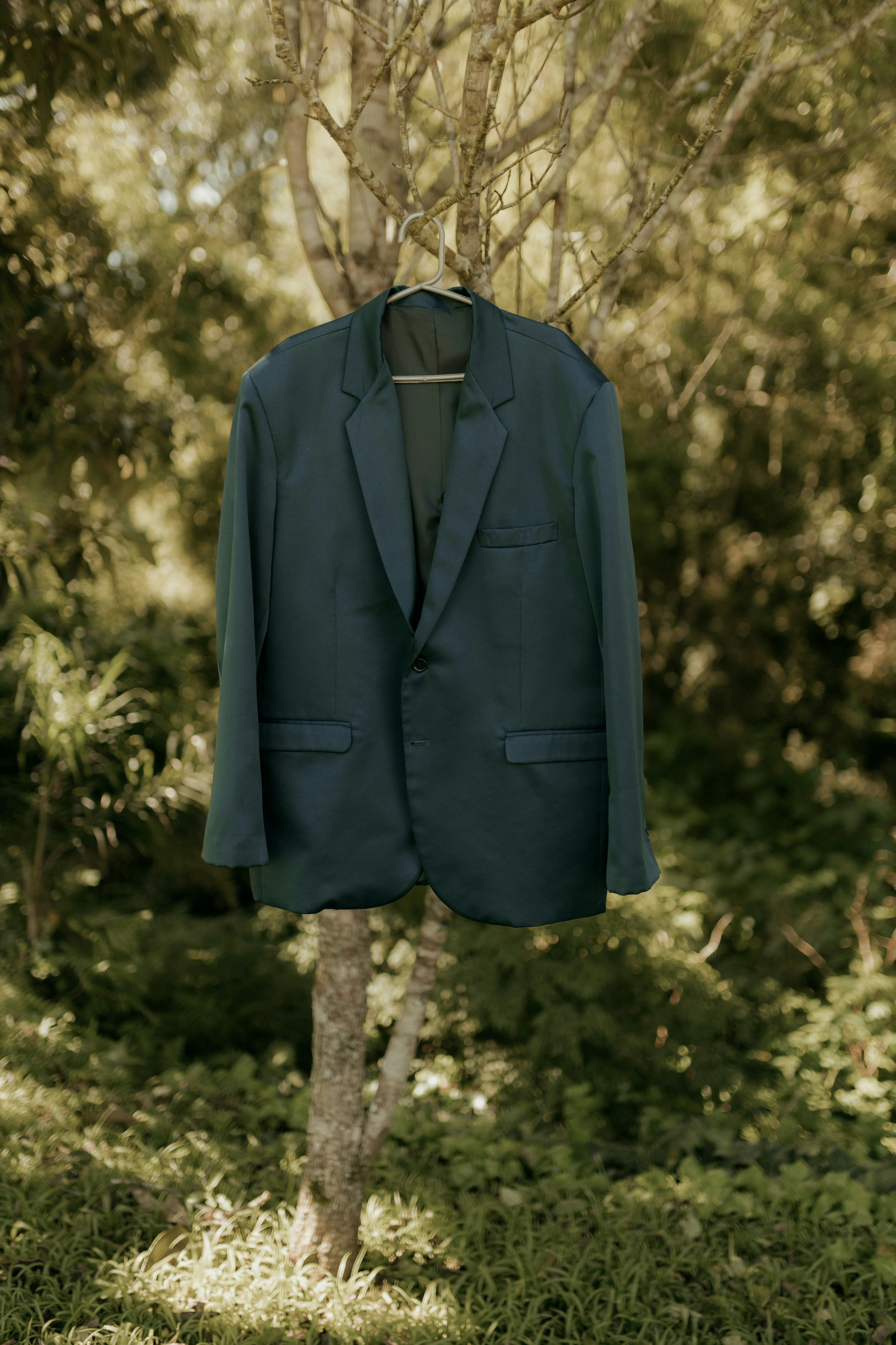 Ein dunkelblaues Sakko hängt an einem Baum.