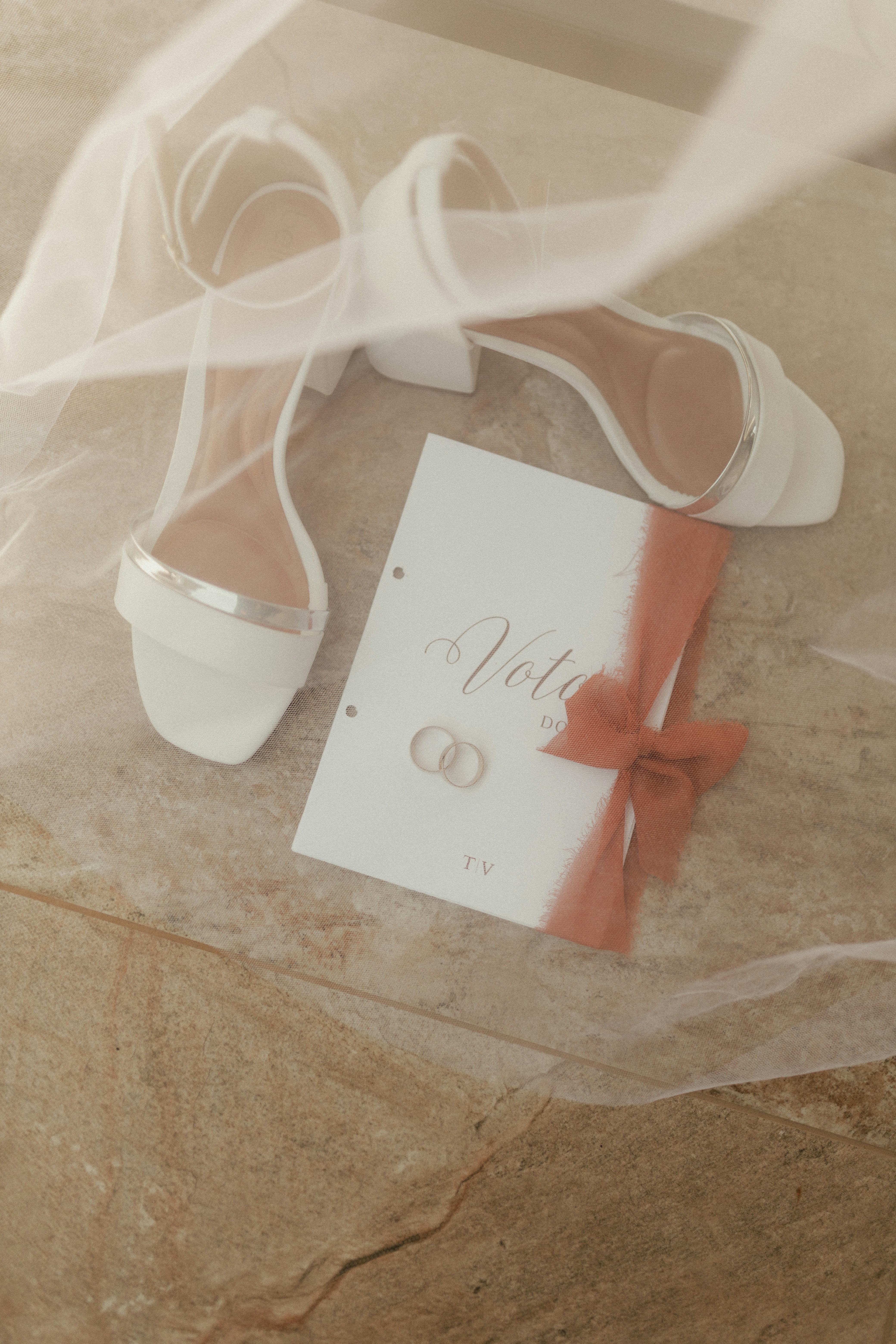 Tacones blancos de boda con anillos y libro de votos