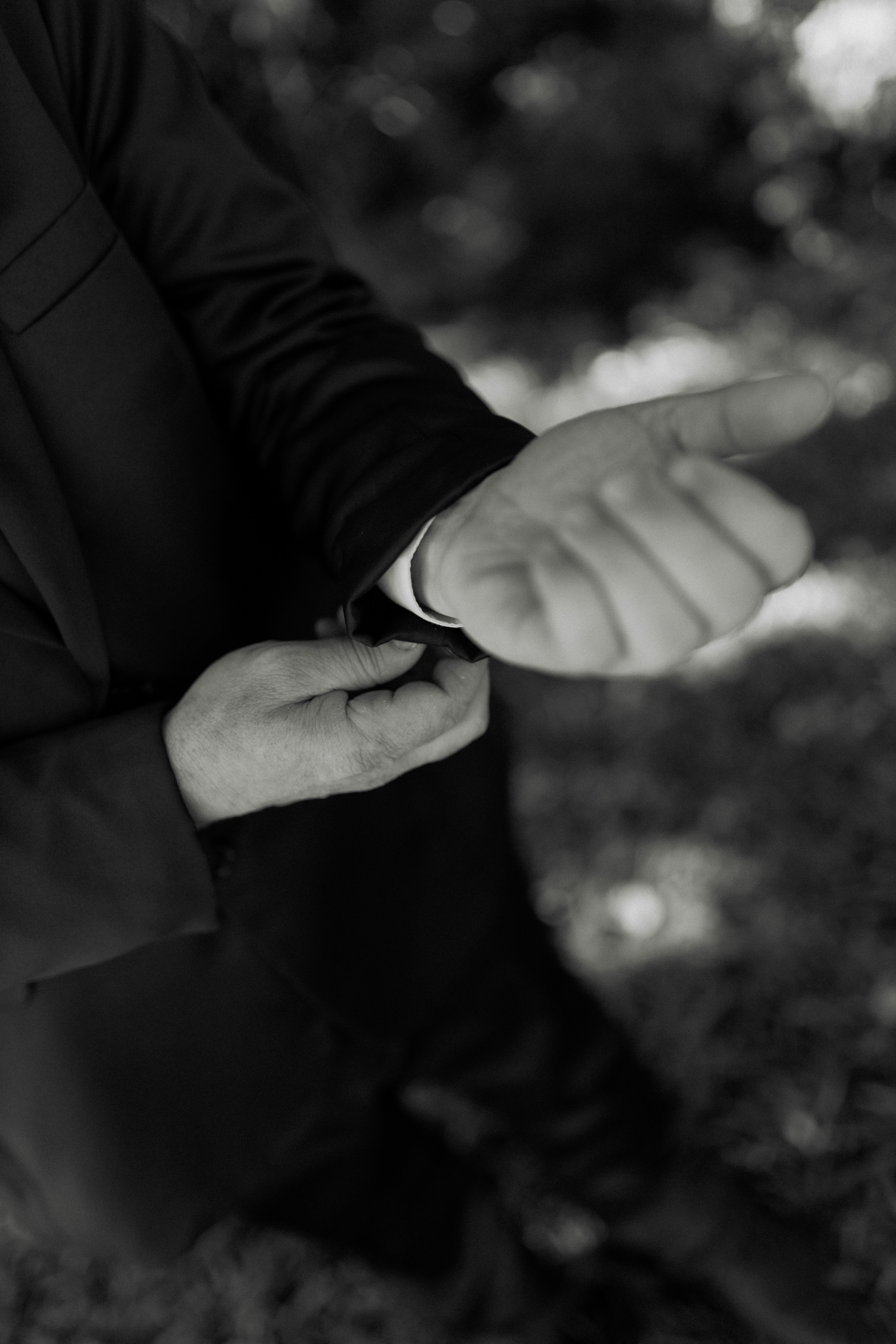 Man adjusting his suit cuff in black and white.