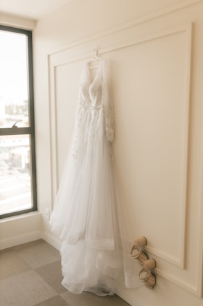 Wedding dress on hanger in bridal salon room with shoes