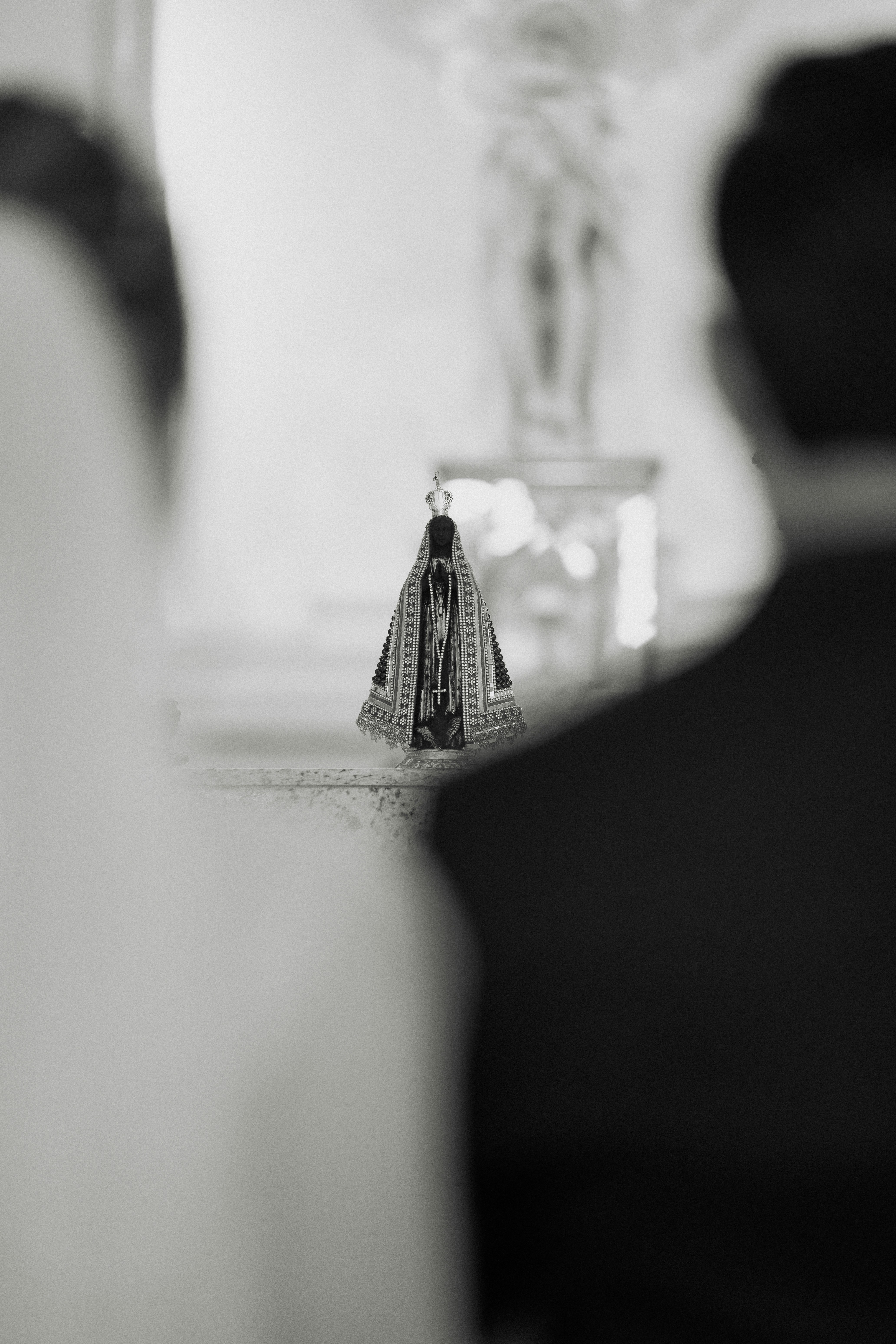 Small religious statue between two blurred figures