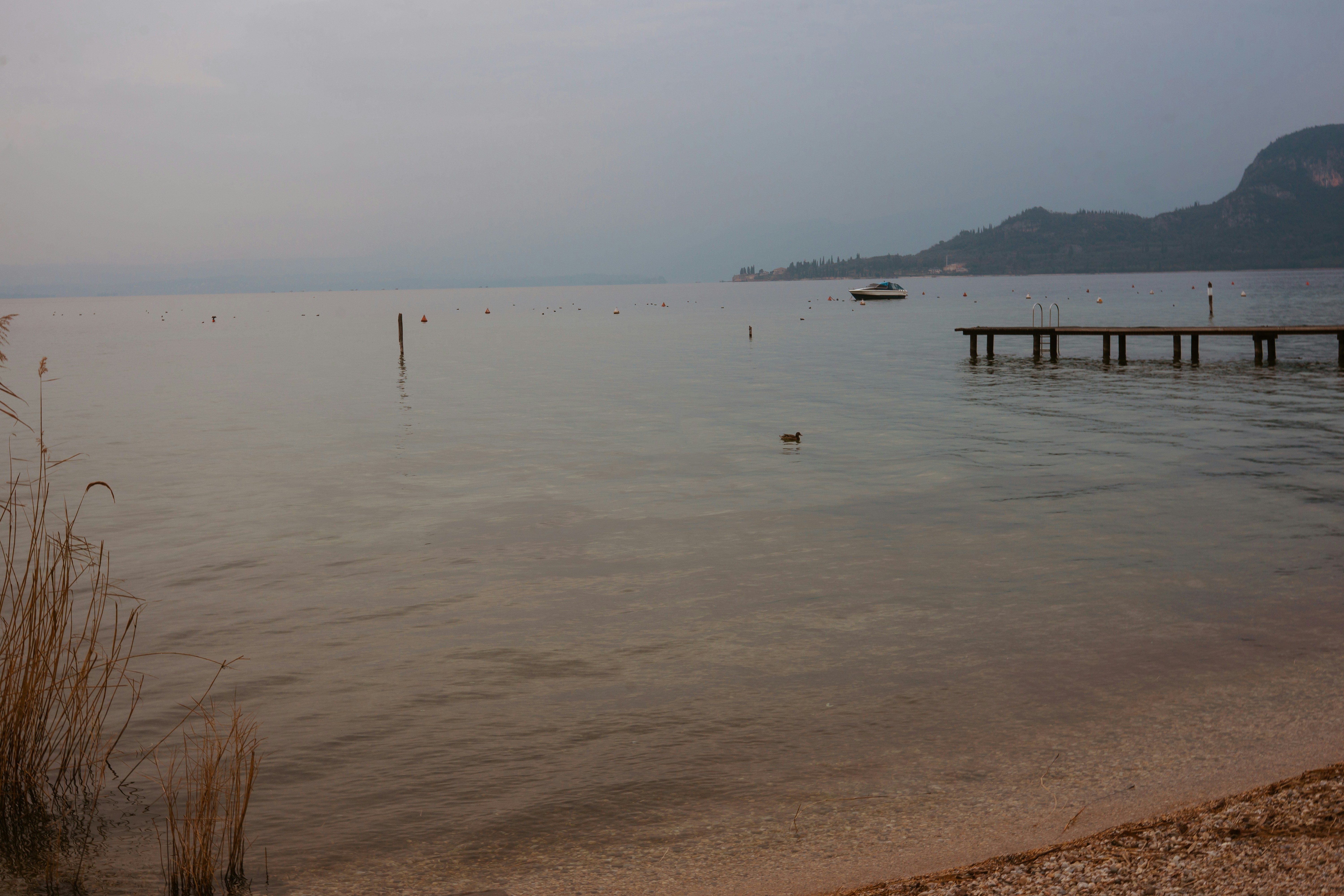 Calm lake with a pier and distant mountains