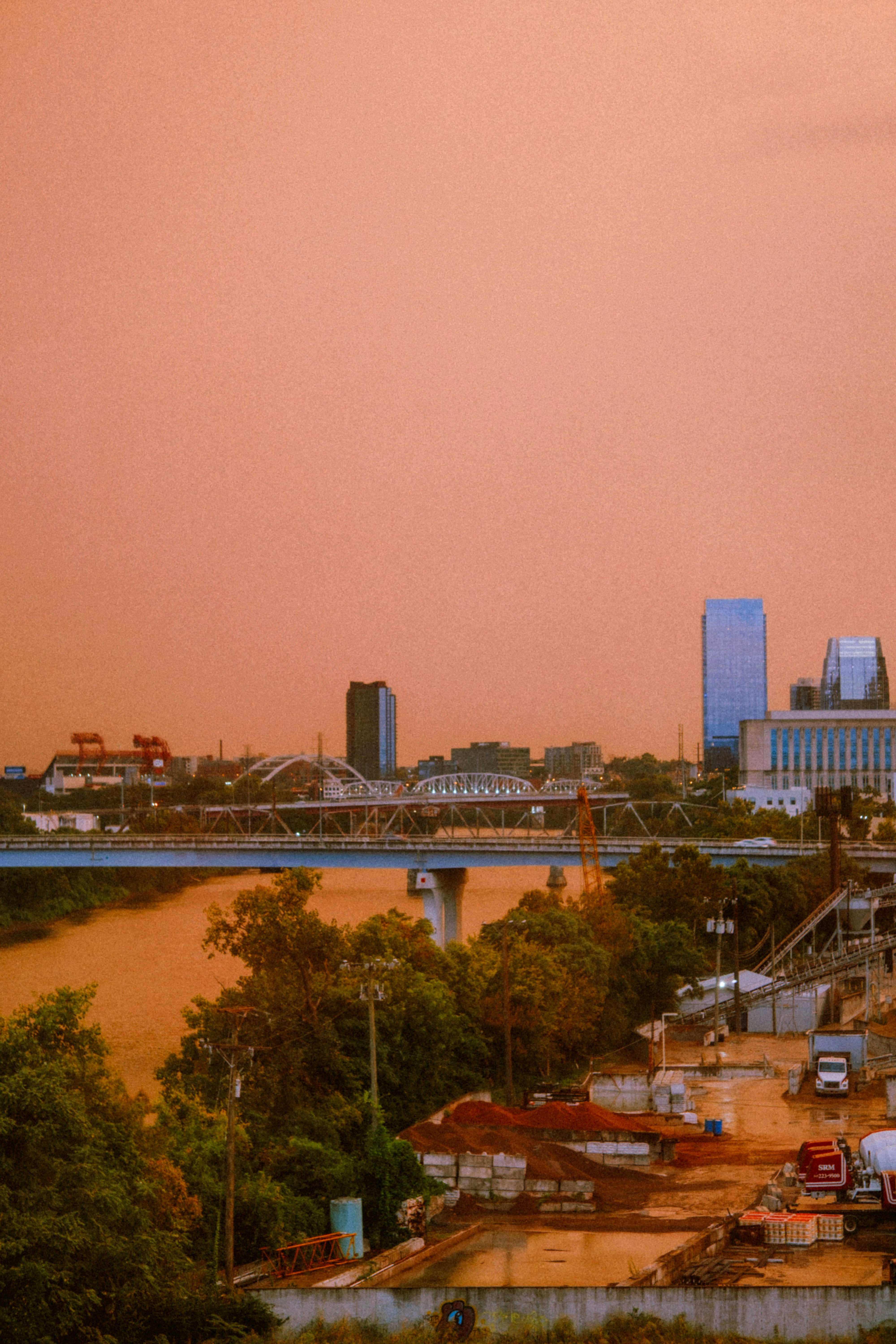 Cityscape with river and construction site at sunset.