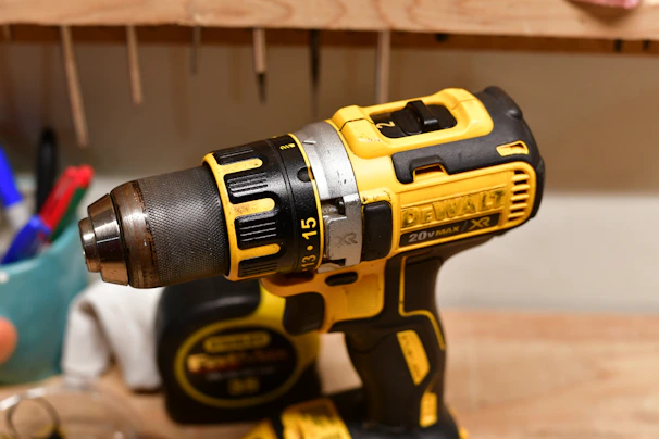 Yellow and black cordless power drill on a workbench.