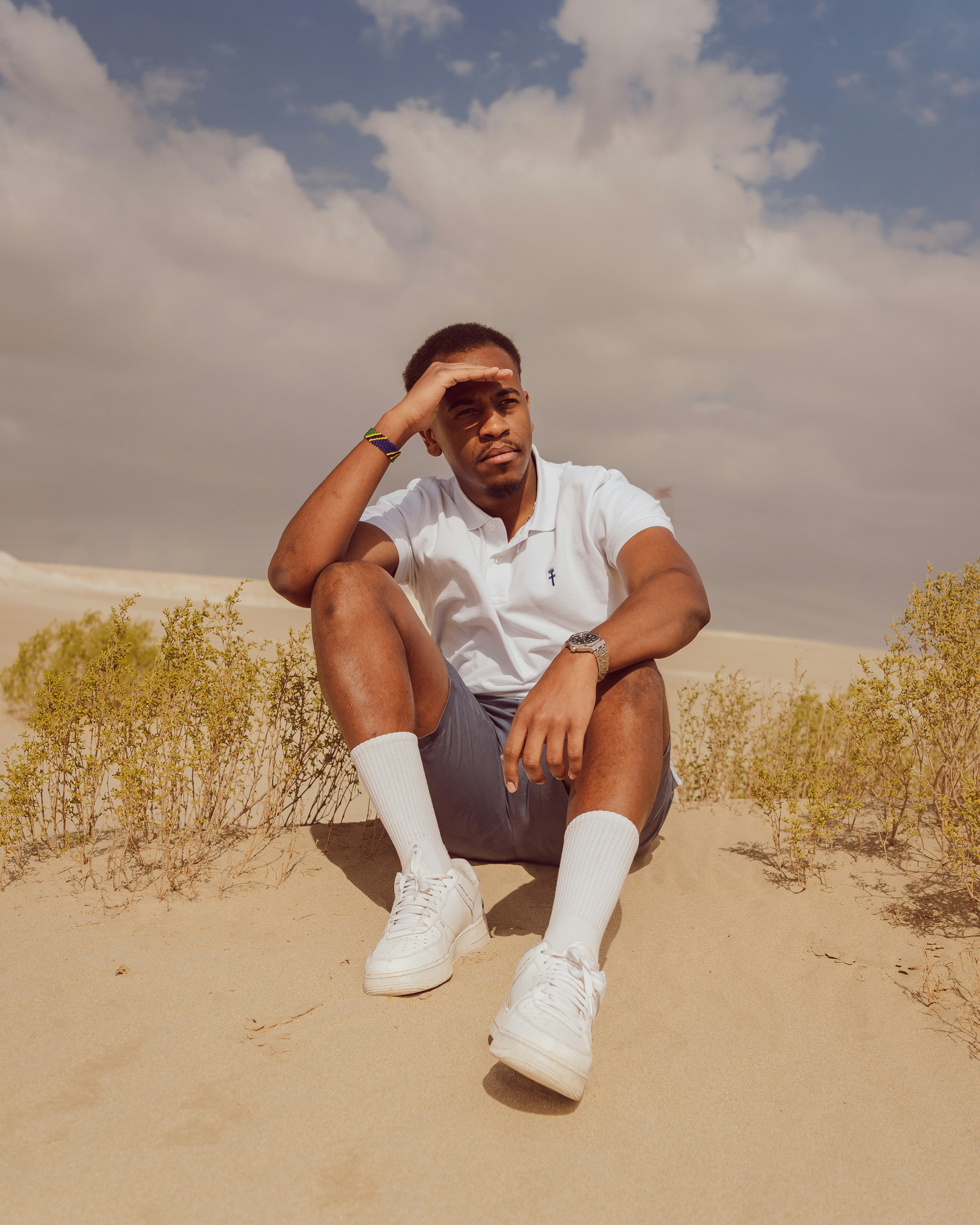 砂丘に座り、日差しから目を守る男