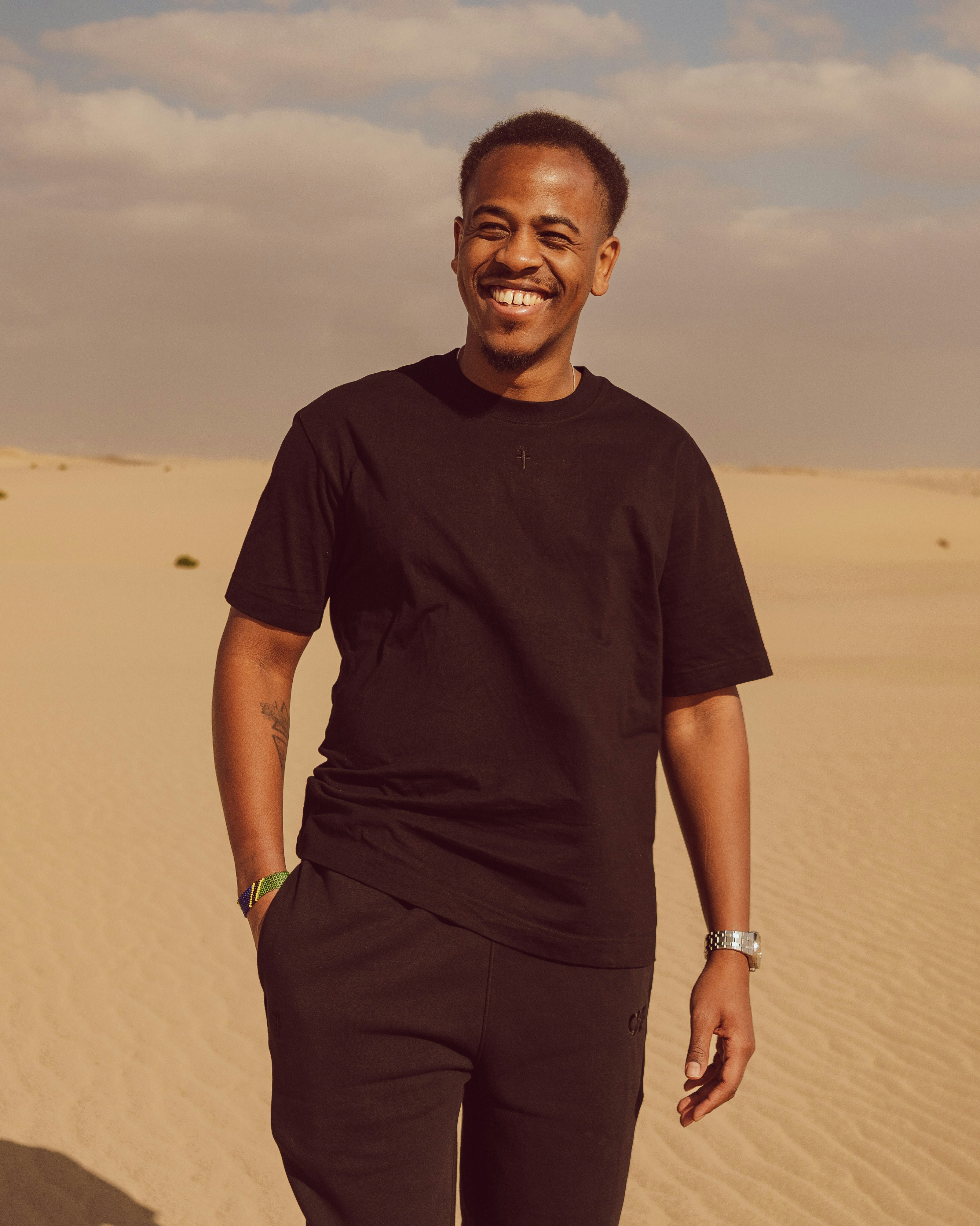 砂漠の黒いTシャツを着た笑顔の男。