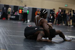 Two wrestlers grappling on the mat during a match