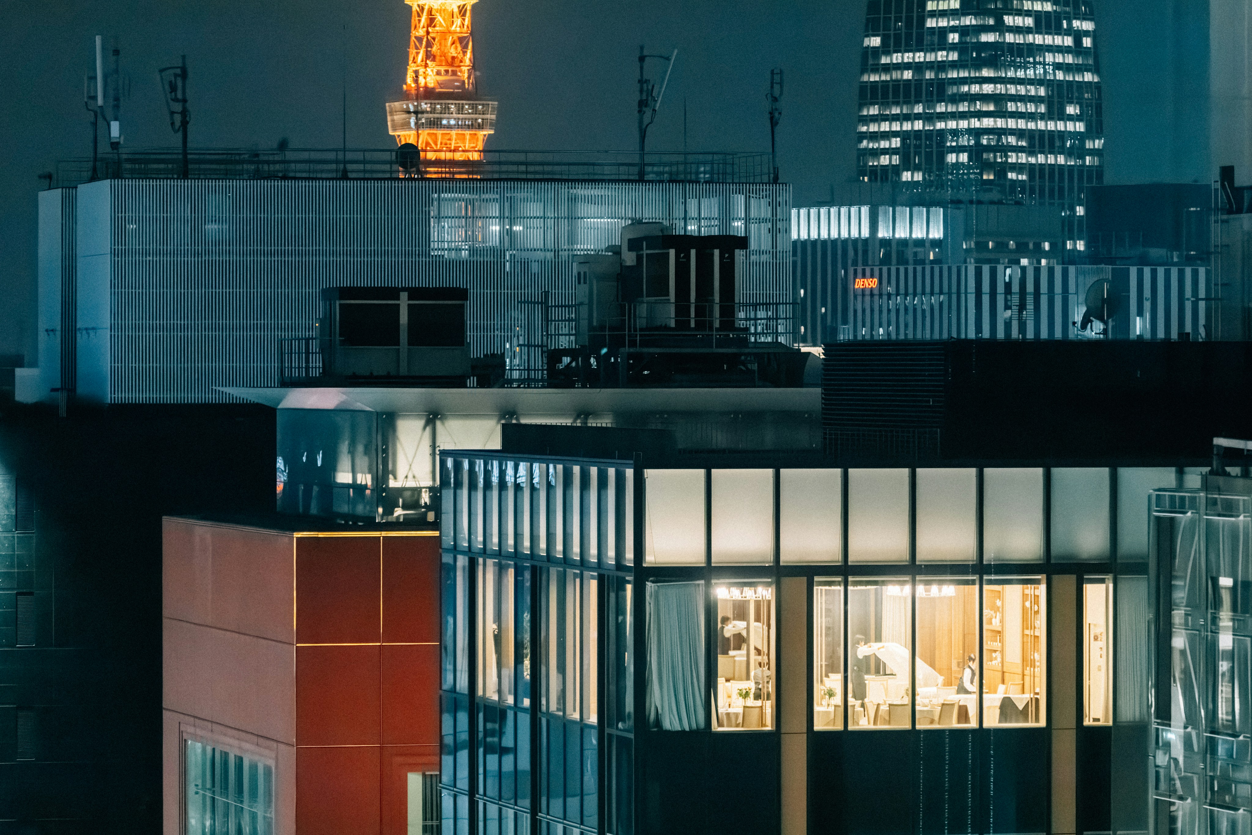 Cityscape at night with illuminated buildings and tower.