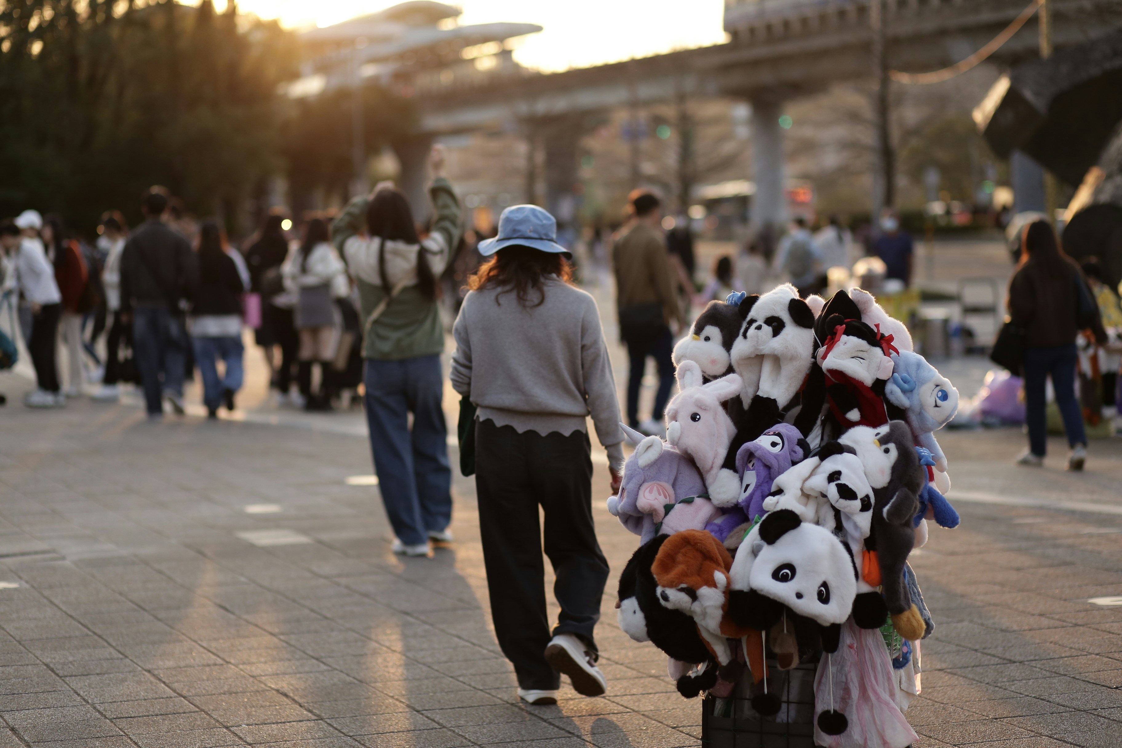 People walking past a display of stuffed animal hats.