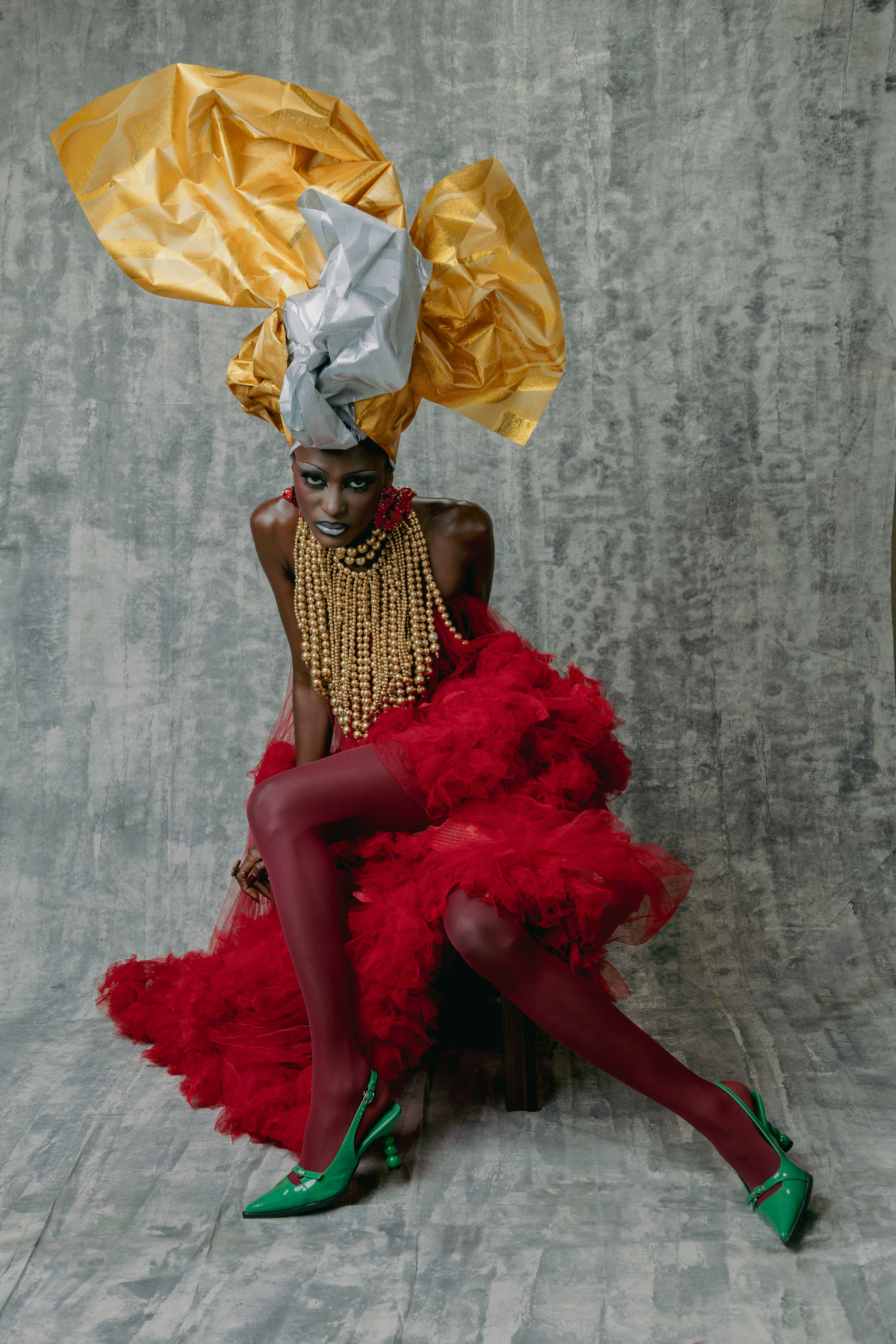 大きなヘッドドレスと赤いドレスを身に着けた華やかな衣装の女性