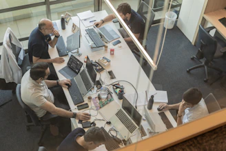Four people working at desks in a modern office.