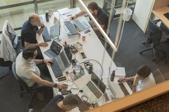 Four people working at desks in a modern office.