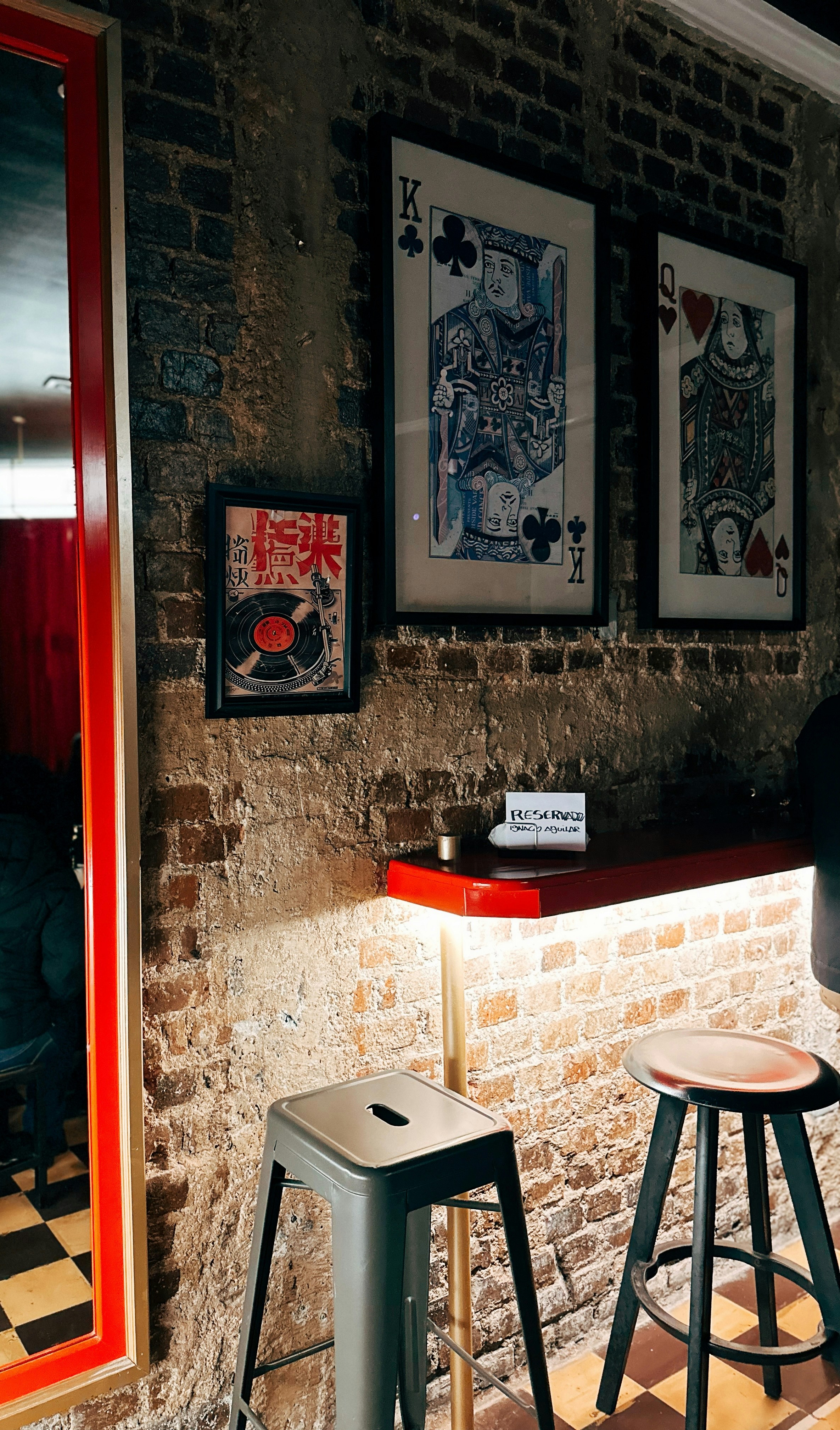 King and queen playing cards framed on brick wall.