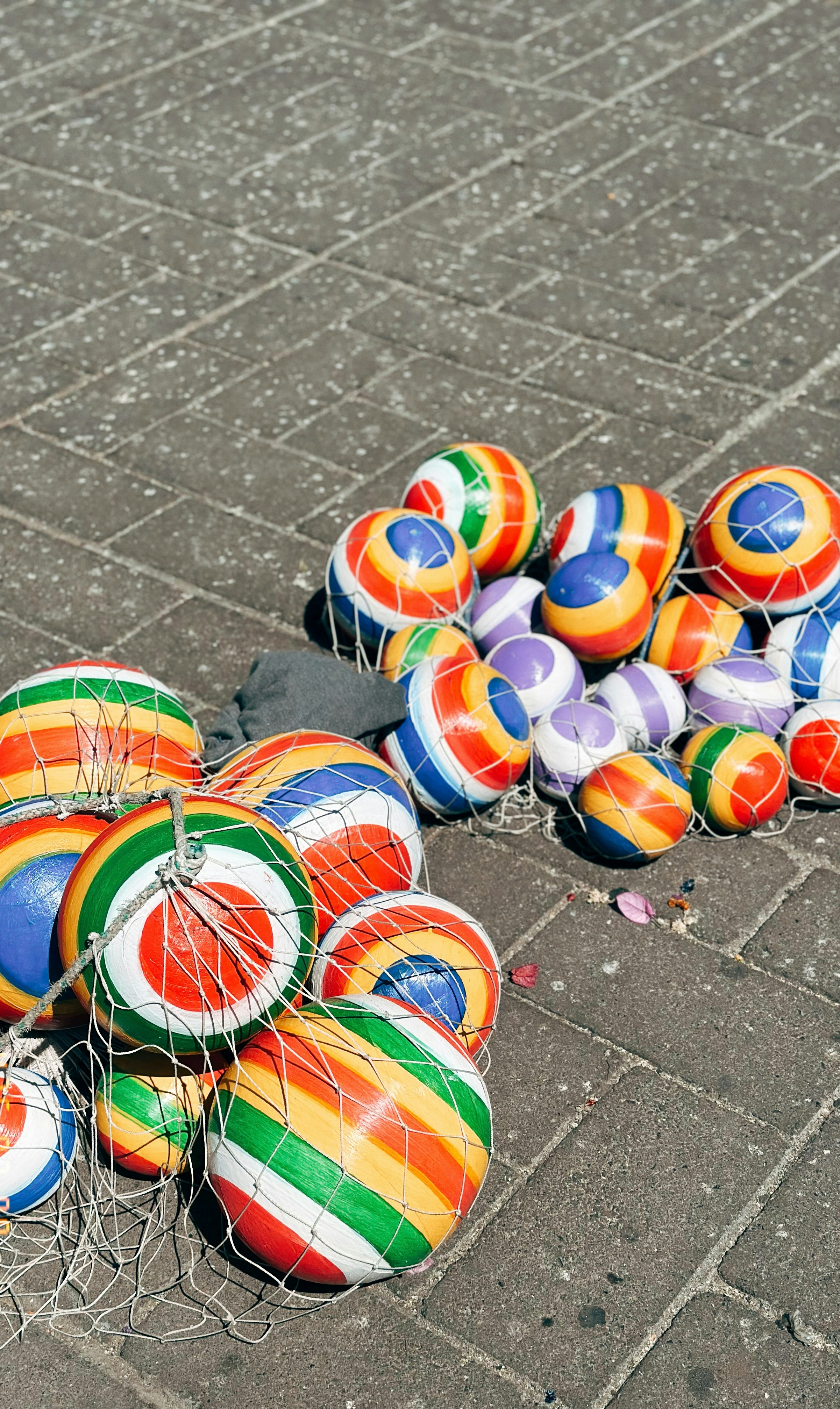 Colorful striped balls in nets on pavement