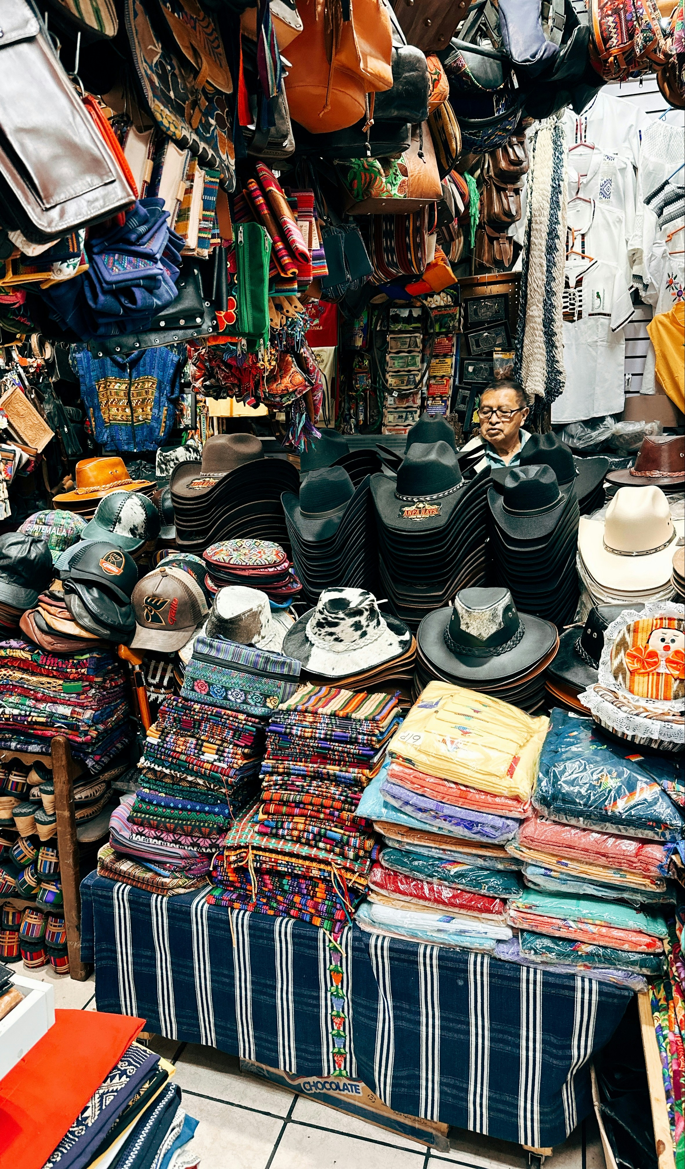 A market stall filled with hats and textiles.