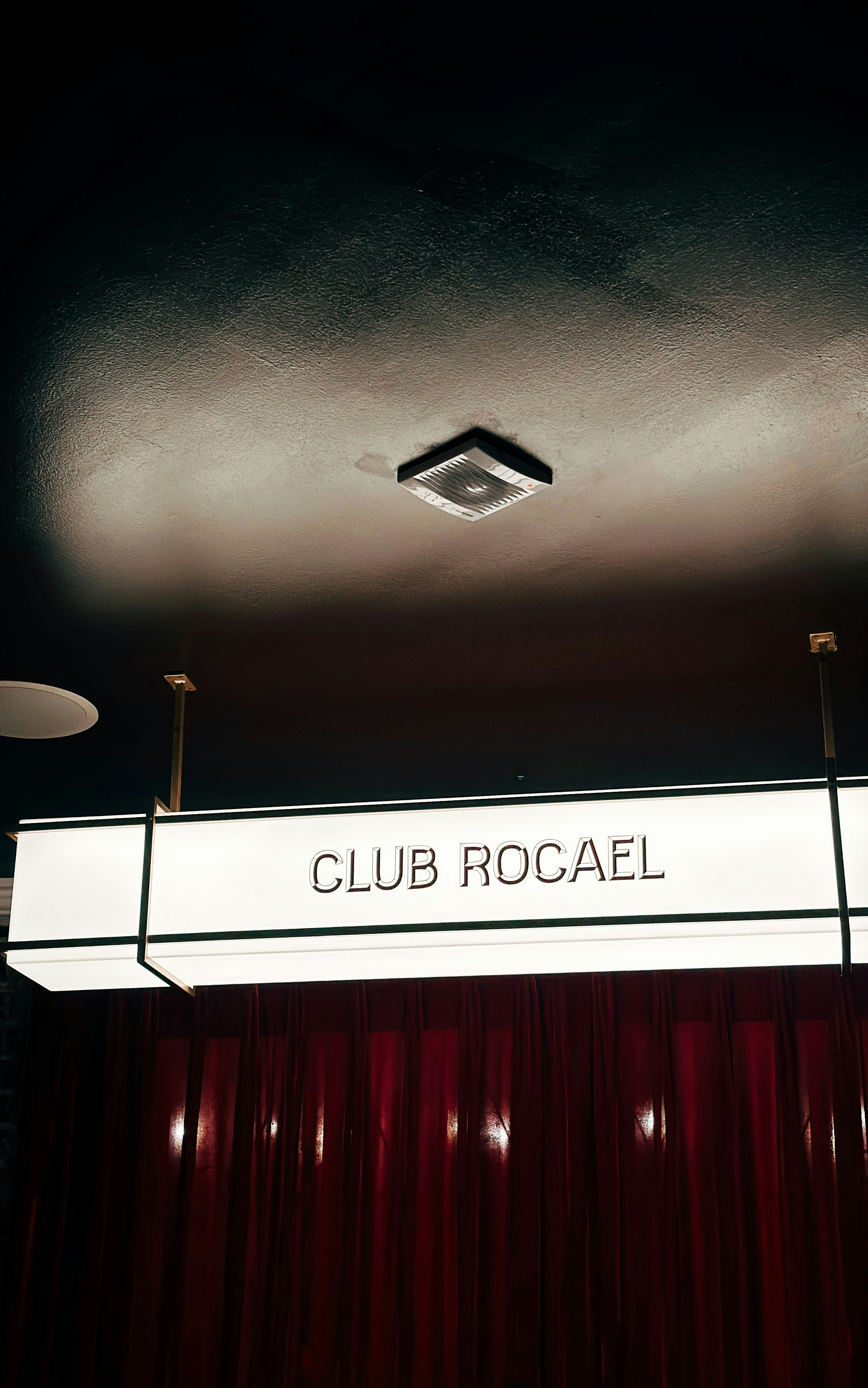 Club rocael sign above red velvet curtains