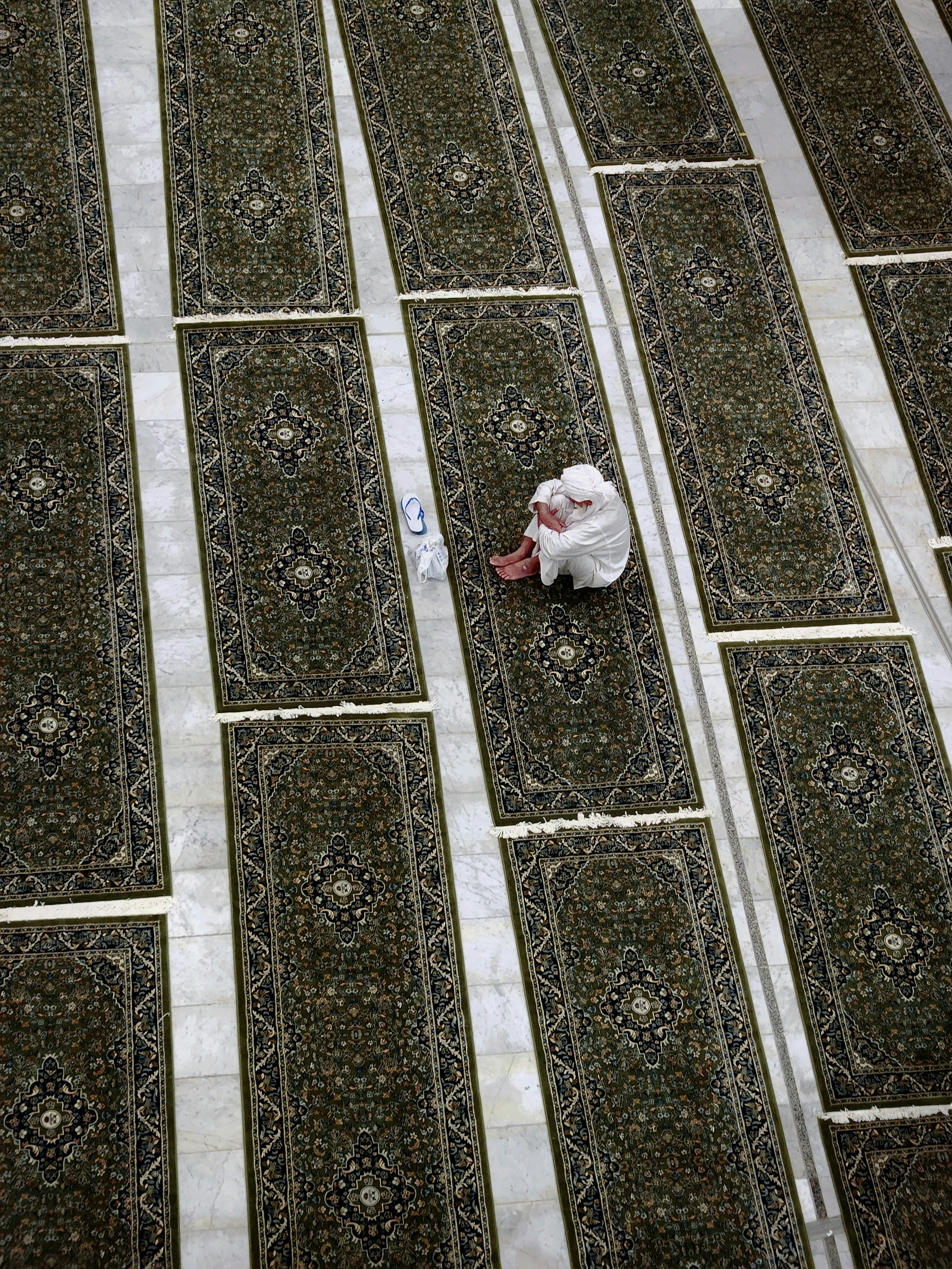 Man praying alone on a patterned rug