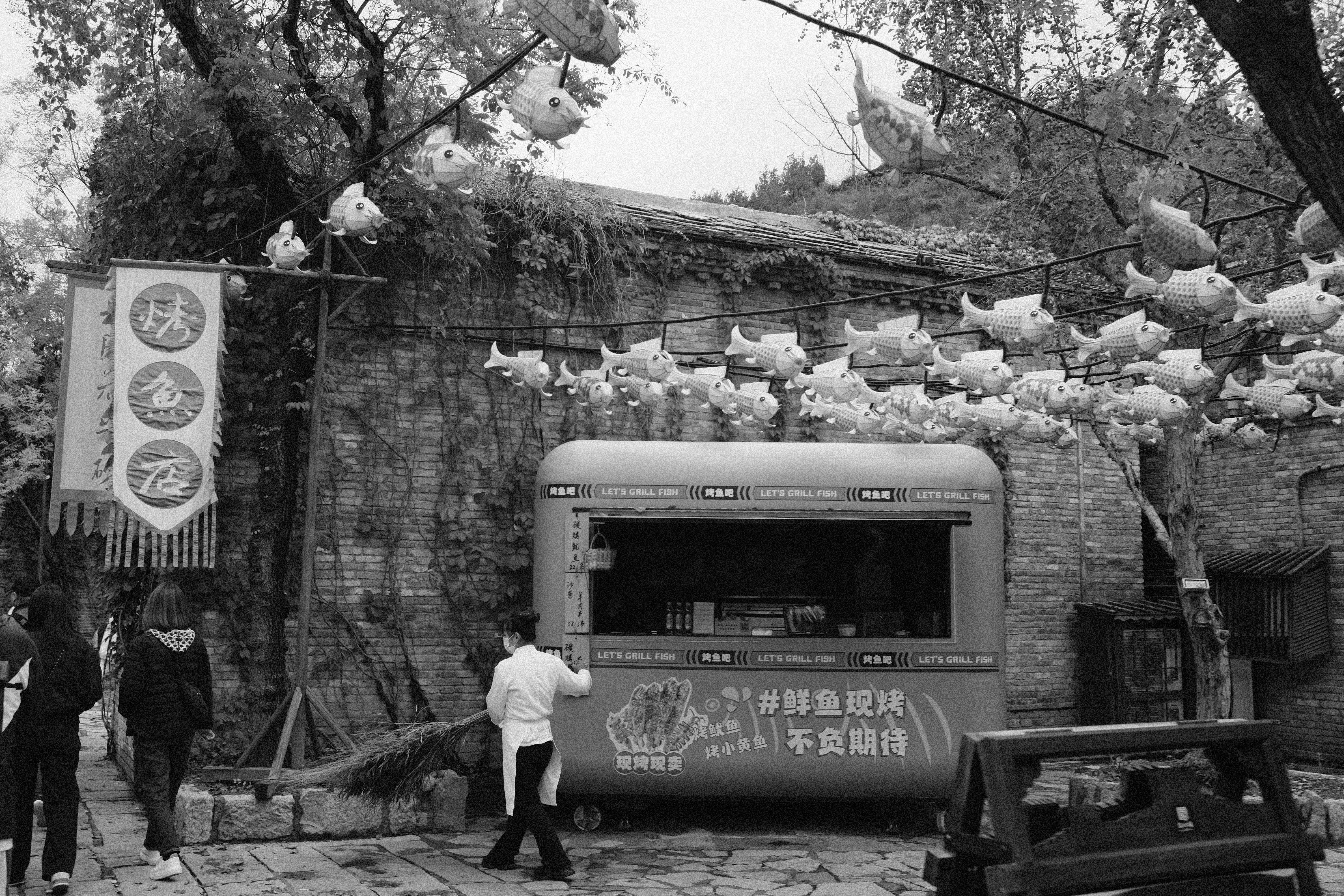 A food truck parked near a stone building with trees.