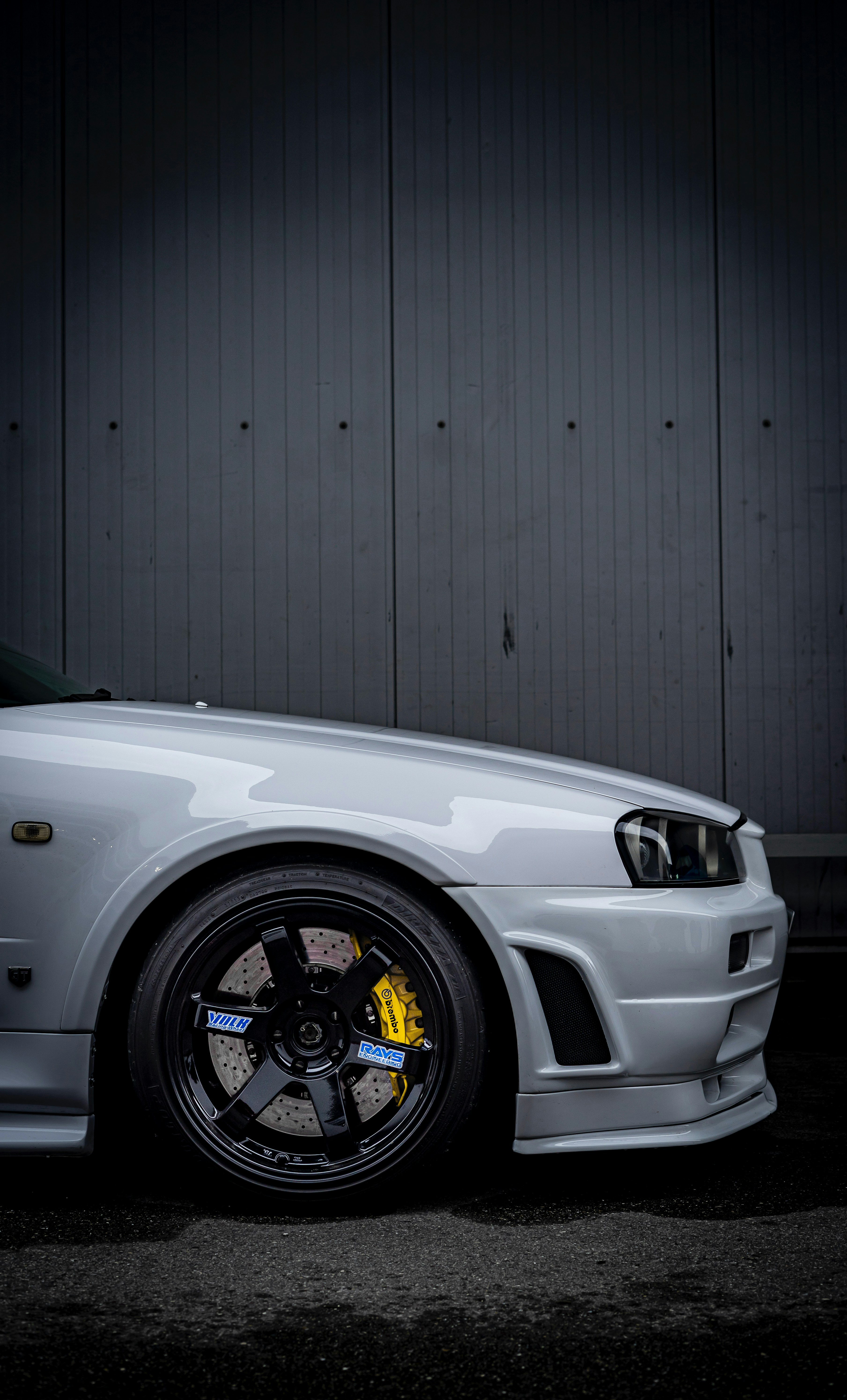 White sports car with black rims and yellow brakes