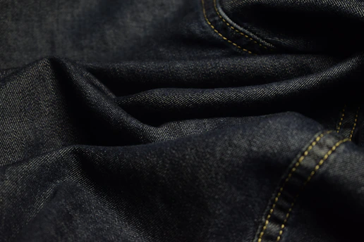 Close-up of dark blue denim fabric with stitching